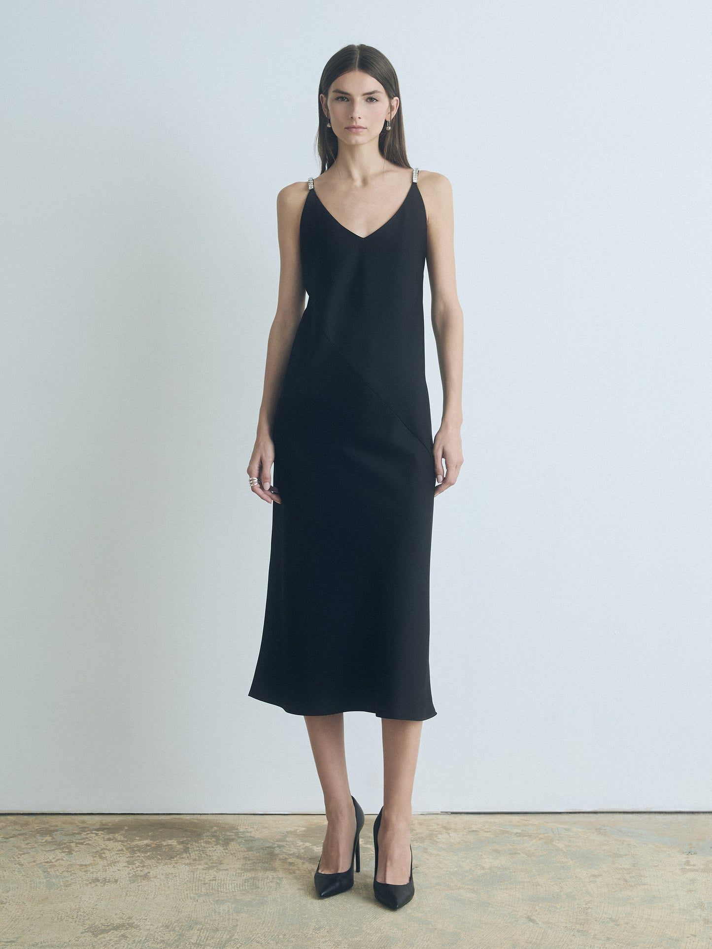 Model wearing black judith and charles Pearle satin bias slip dress with V-neck and shoulder embellishments