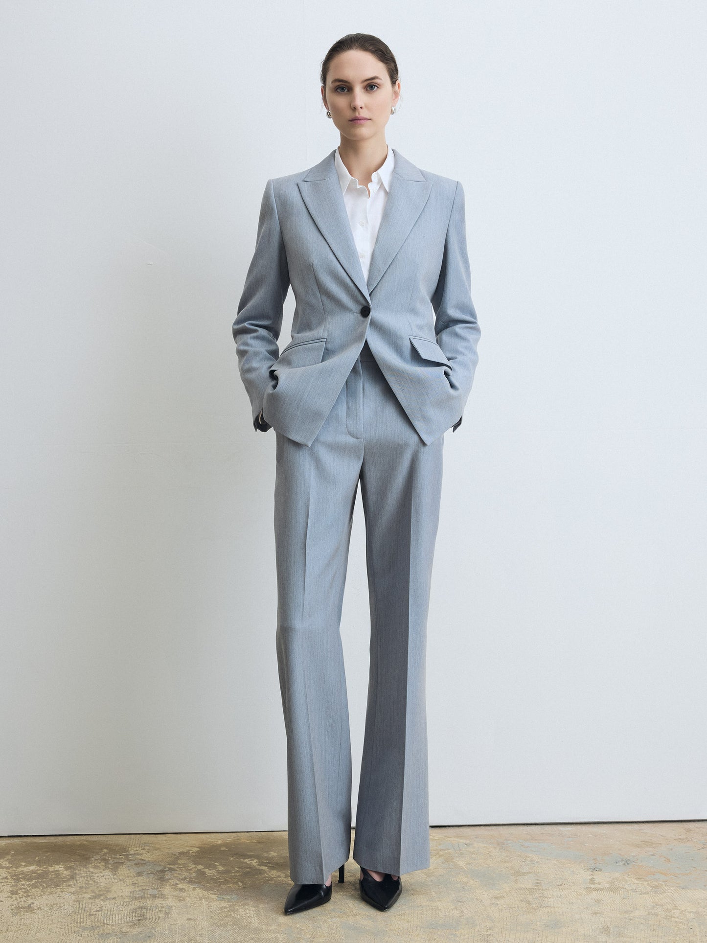 Woman wearing a light blue suit with a white shirt against a plain background