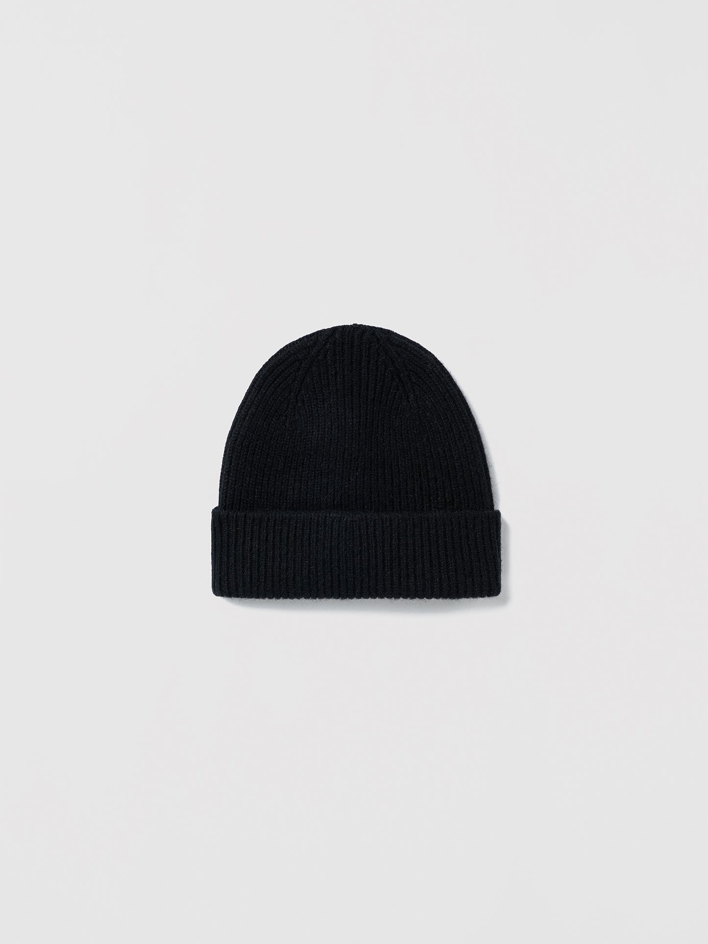 Flat lay of ribbed black beanie in soft lambswool and Caregora blend, classic silhouette in wool knit, made in Scotland