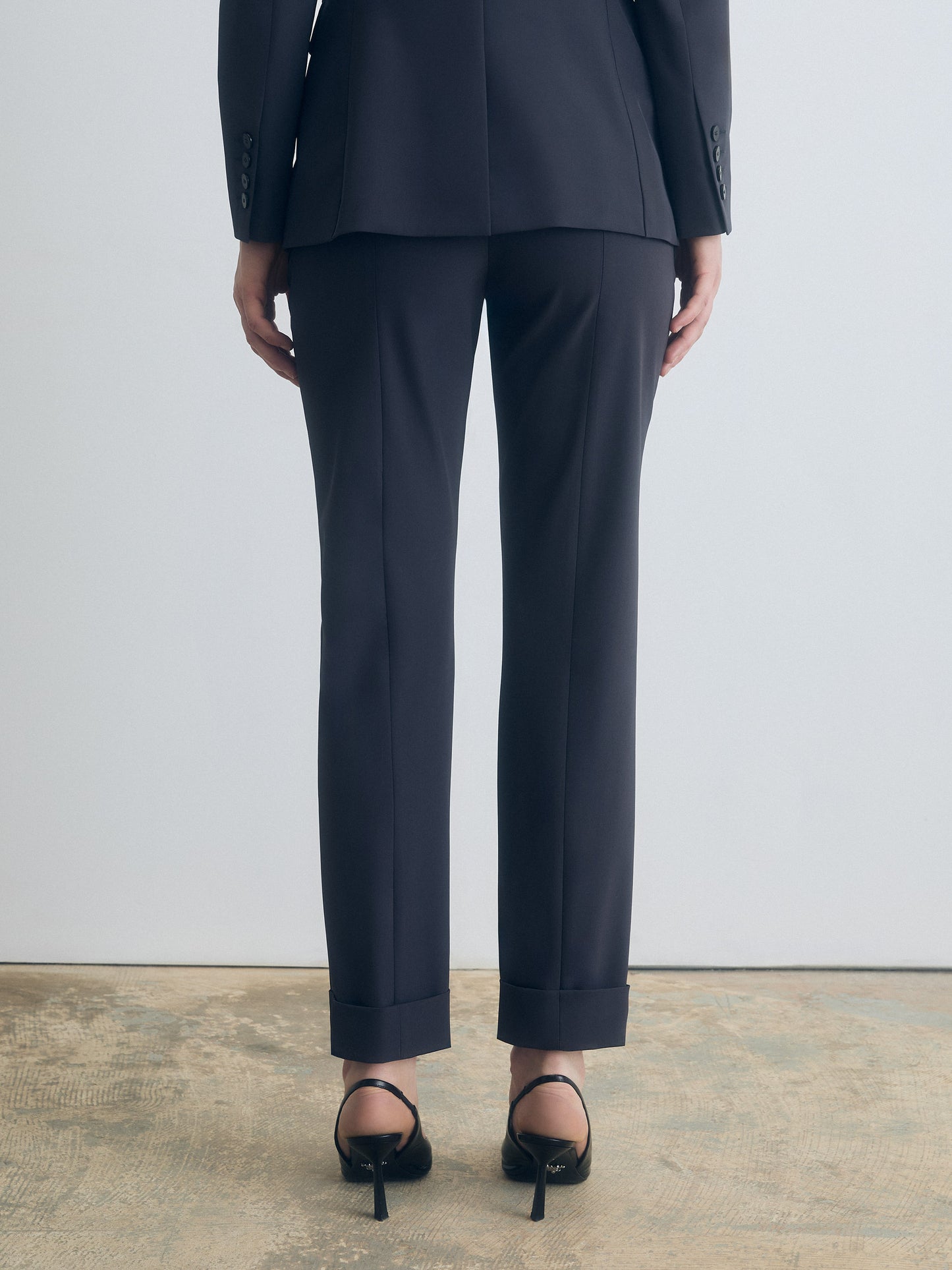 Person wearing a dark grey suit with a plain background