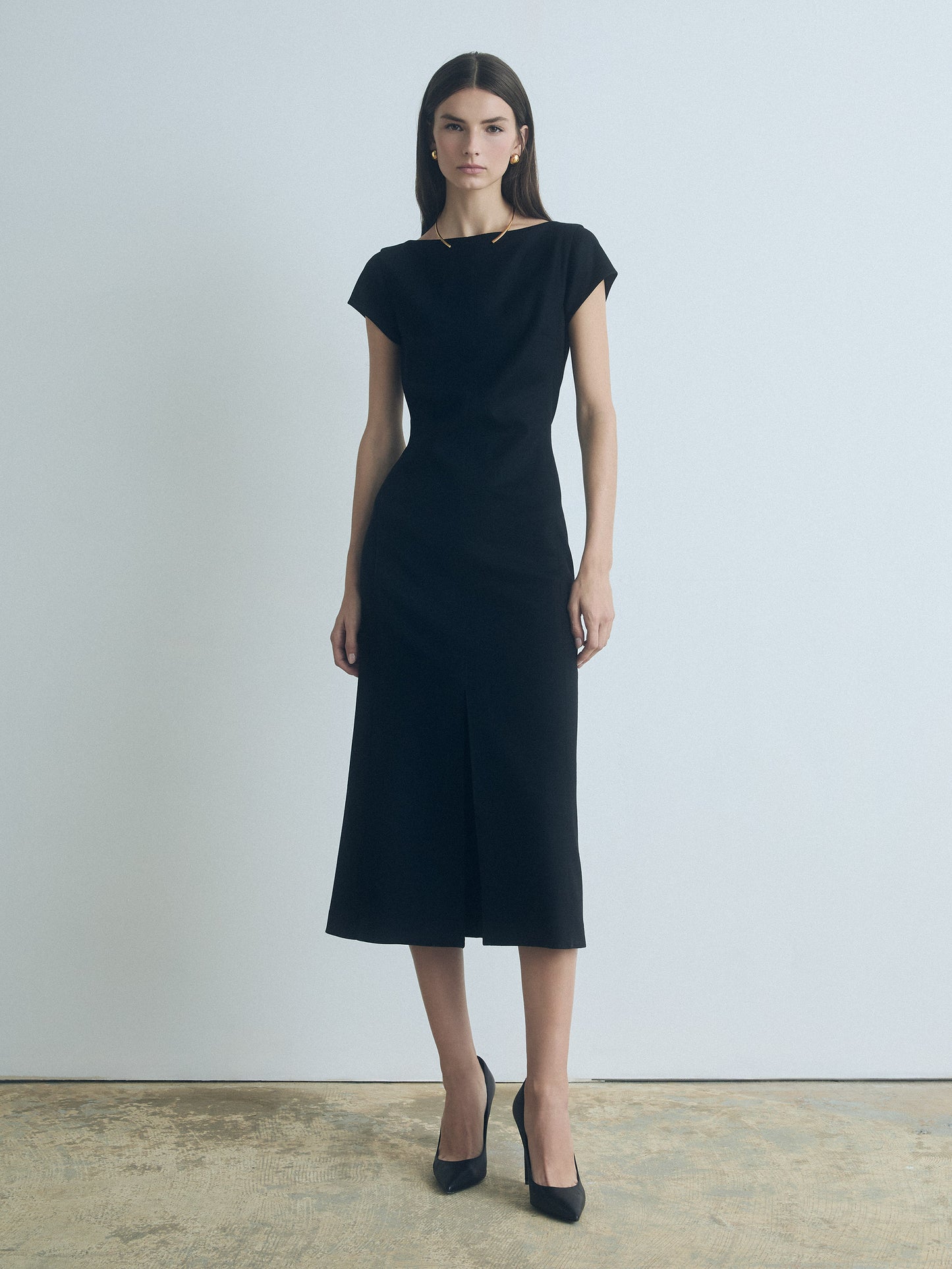 Model wearing a black wool-blend boat neck dress with front slit and invisible back zipper, fully lined, made in Canada from Italian fabric by Judith & Charles.