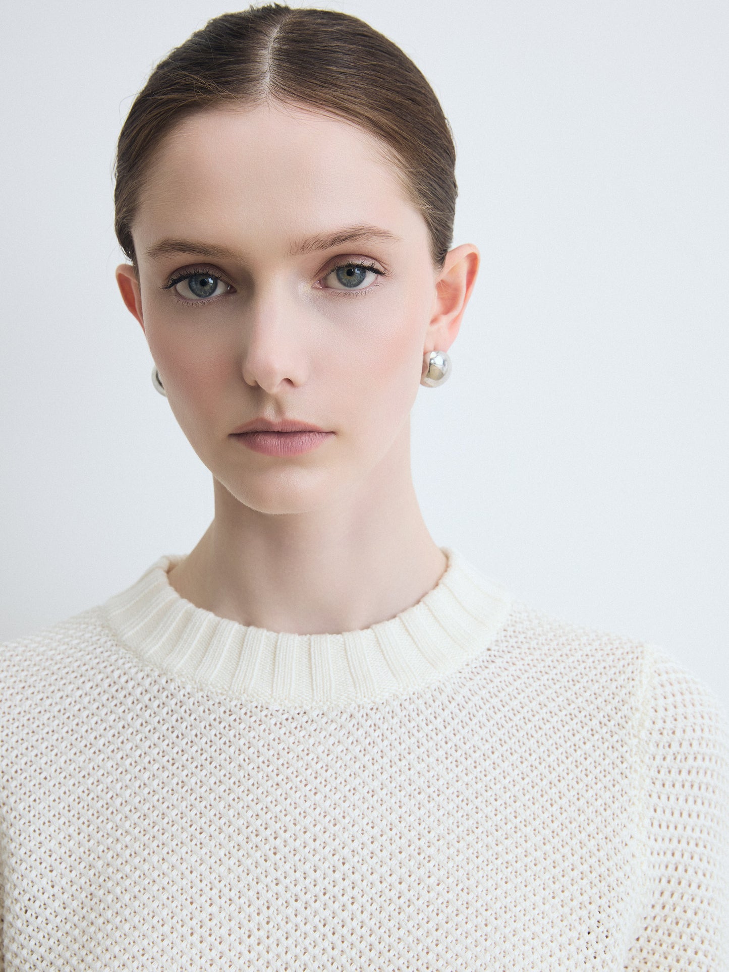 Woman wearing a white sweater against a light background