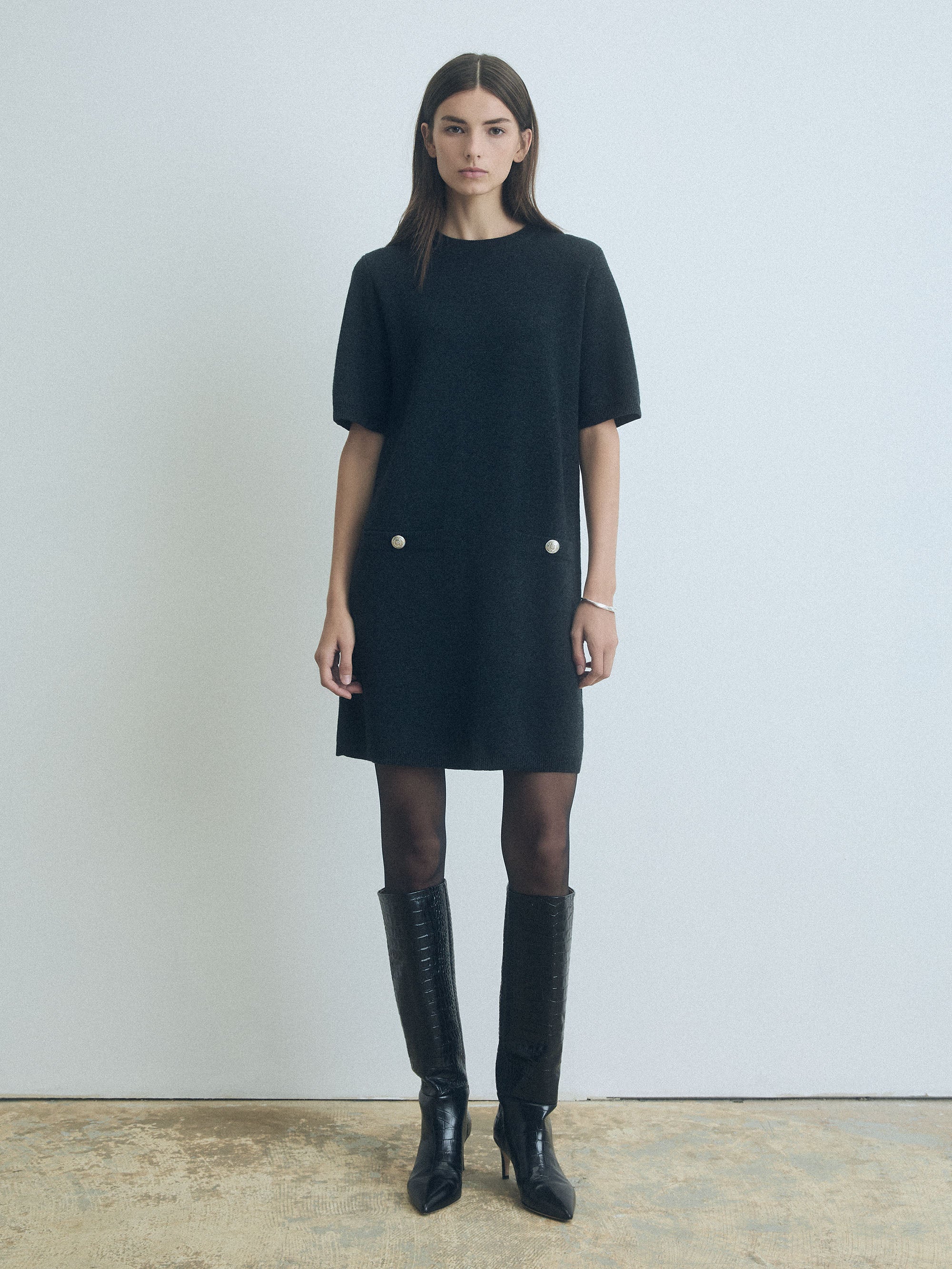 Woman wearing a Charcoal wool-cashmere short-sleeve Milano knit dress with crew neck and two buttoned welt pockets by Judith & Charles