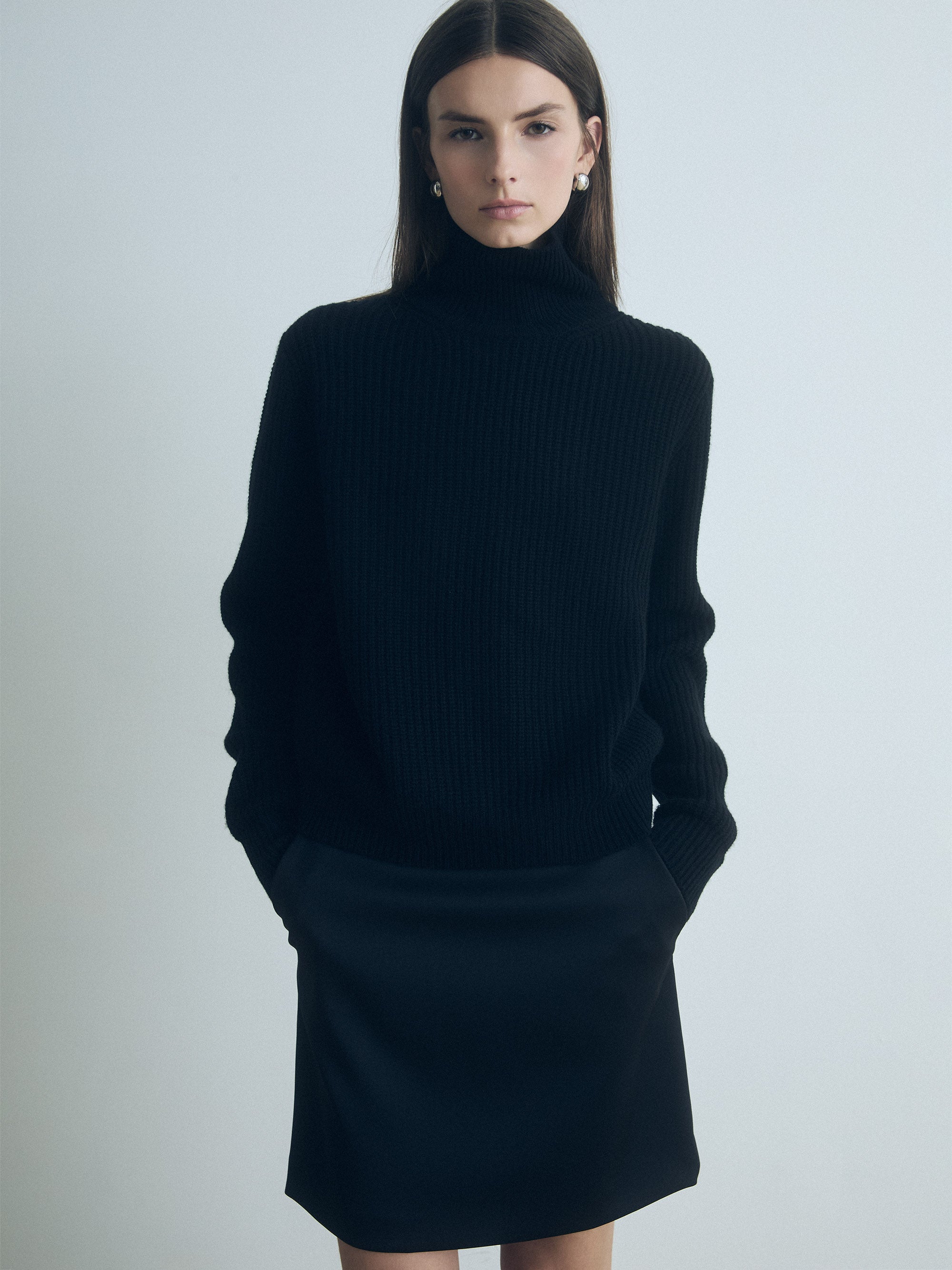 Model wearing a judith and charles black turtleneck and dark pants against a plain background