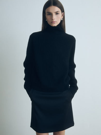 Model wearing a judith and charles black turtleneck and dark pants against a plain background