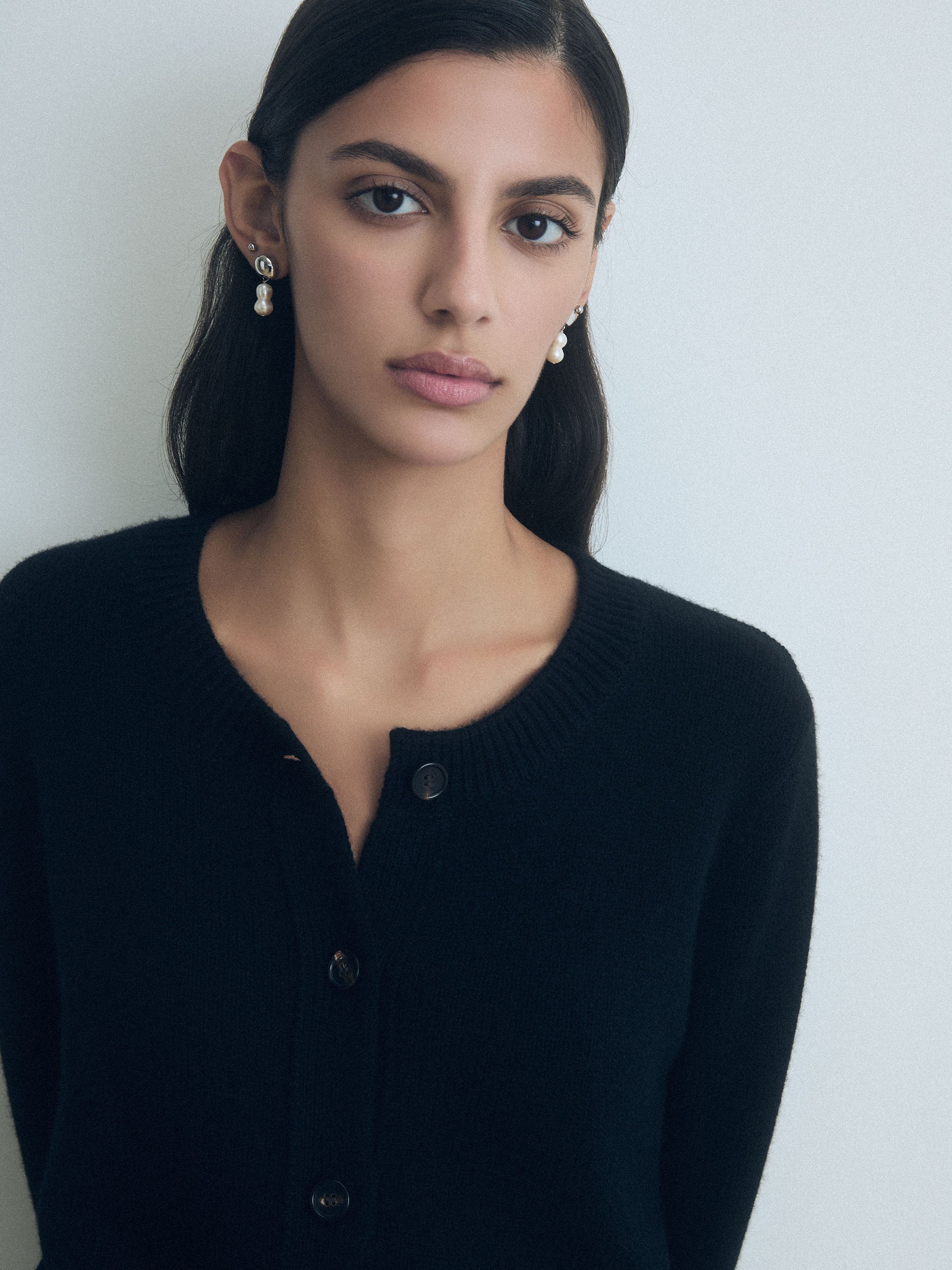 Woman wearing a Black wool-cashmere blend cardigan with crew neck, button front, and two patch pockets by Judith & Charles.