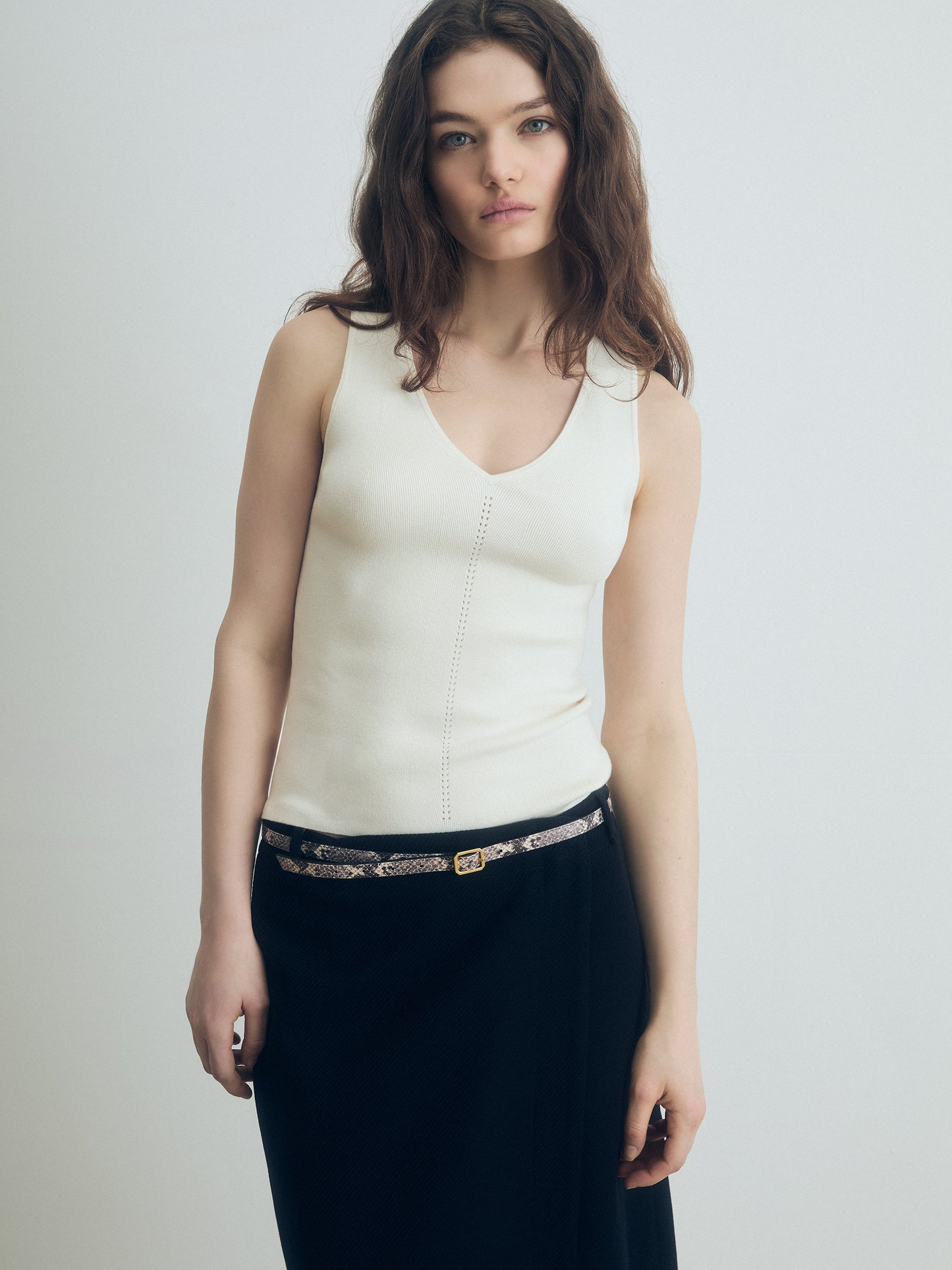 Off‑white V‑neck silk‑cotton shell styled with a black skirt and a slim python belt, shown on‑model.