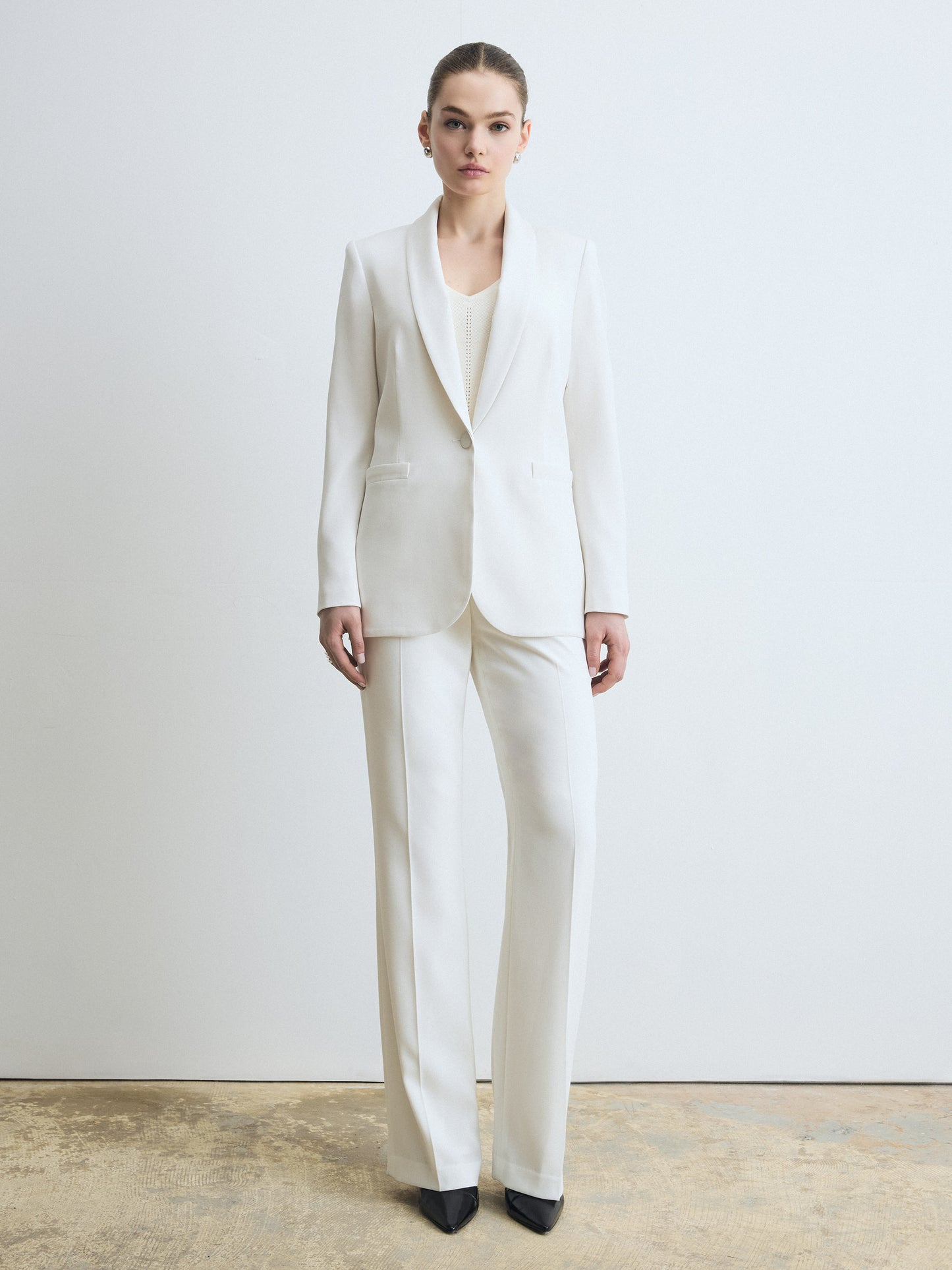 Person wearing a white suit standing against a plain background