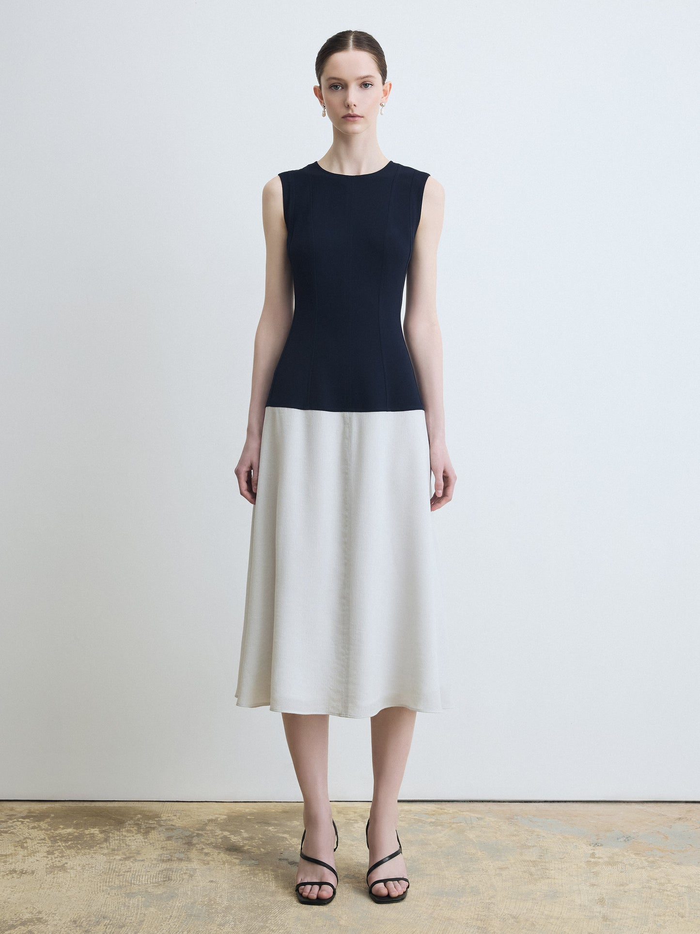 Woman wearing a navy and white dress against a plain background