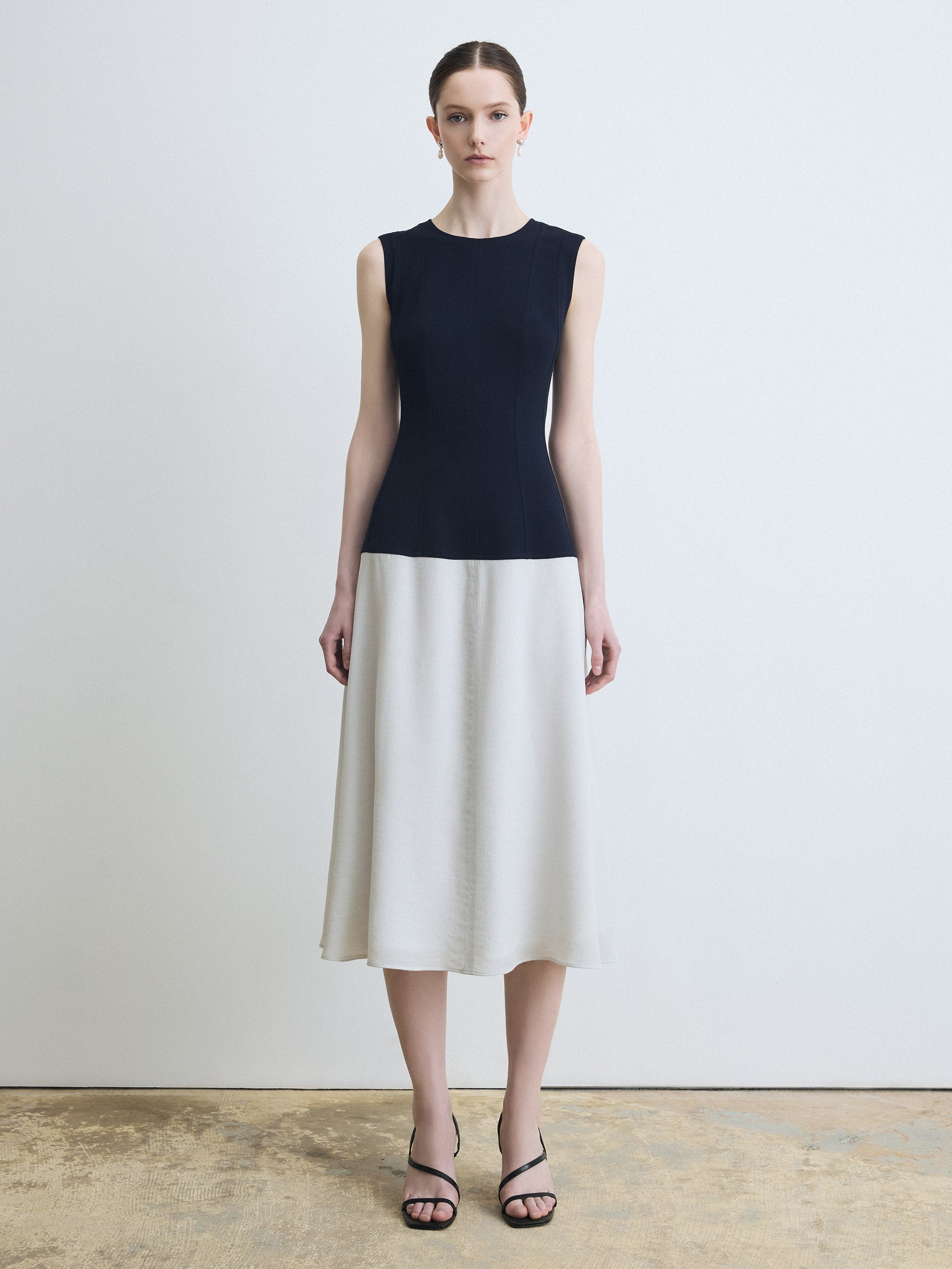 Woman wearing a navy and white dress against a plain background