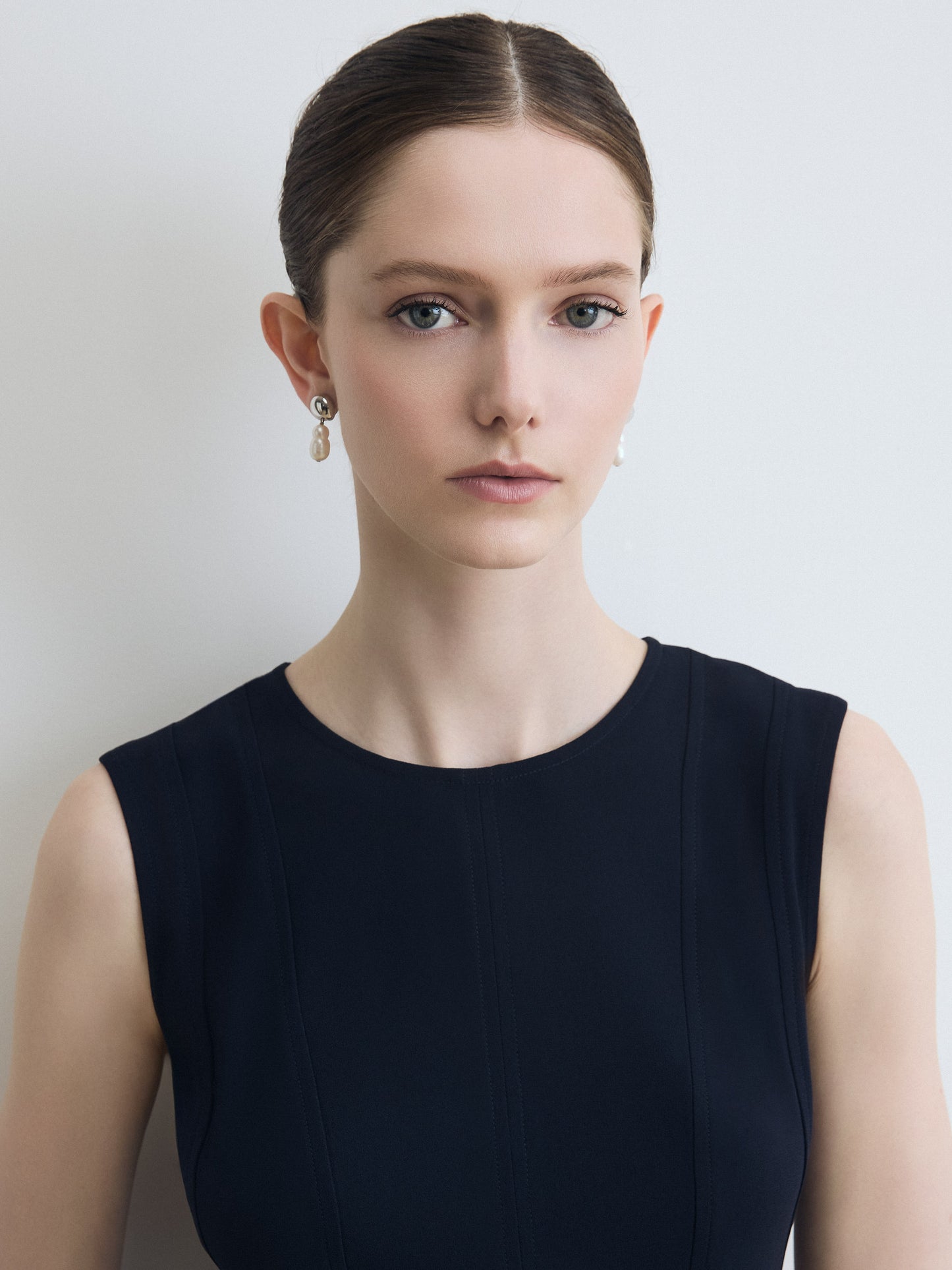 Woman wearing a black sleeveless top against a plain background