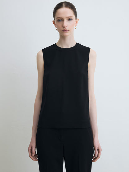 Person wearing a black sleeveless top against a plain background