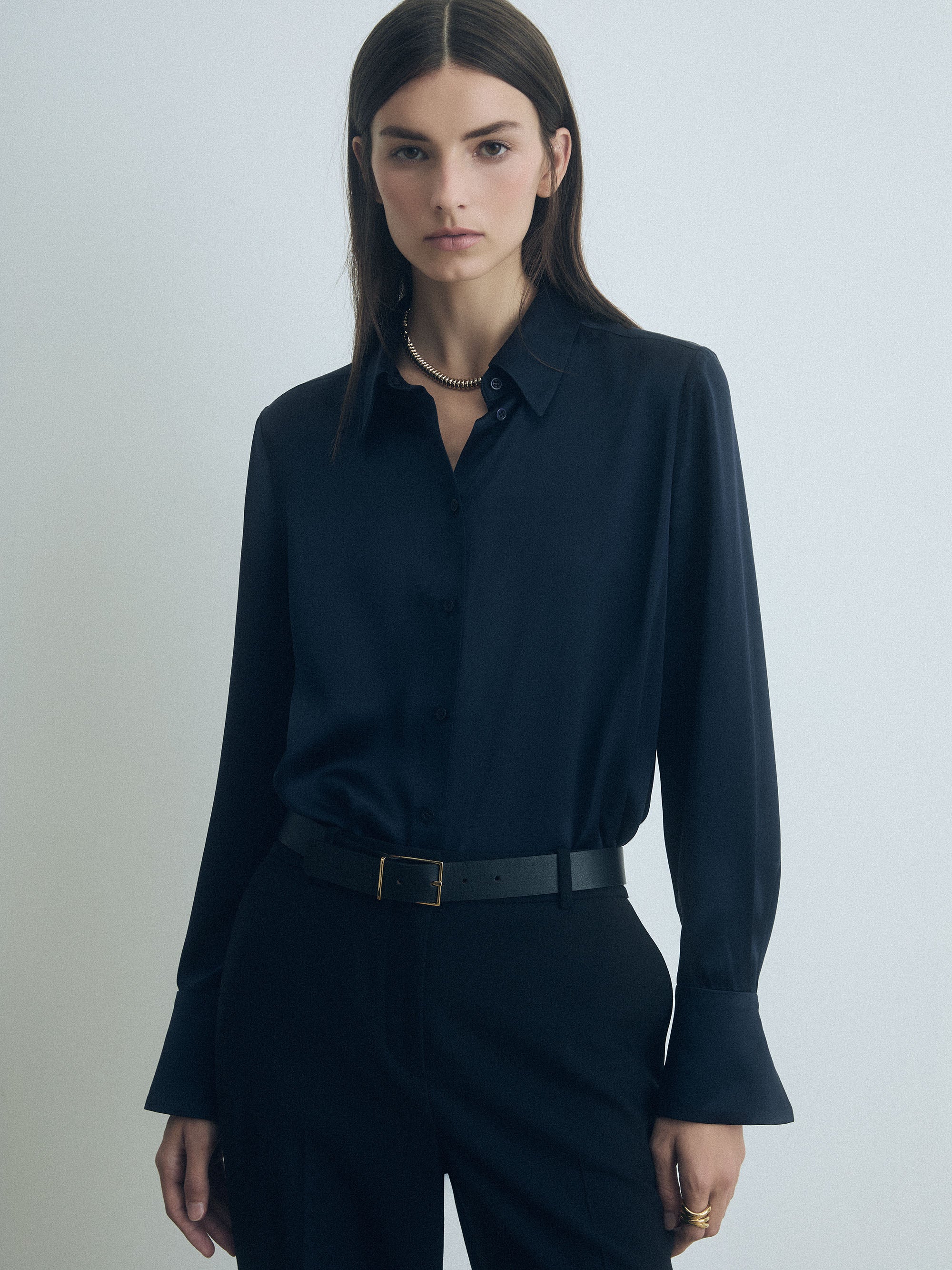 Woman wearing a navy judith and charles blouse and pants against a light gray background