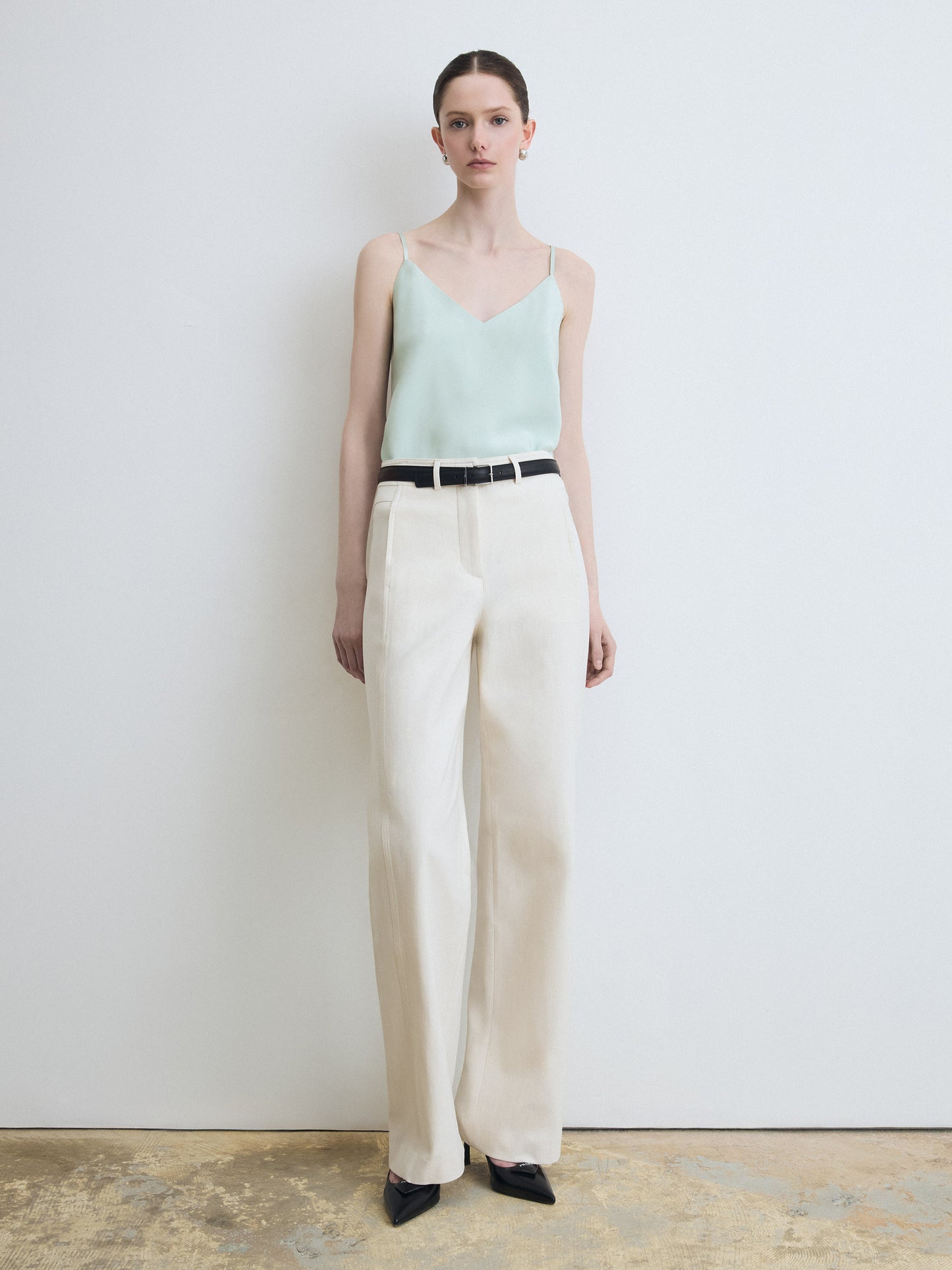 Model wearing mint sleeveless blouse paired with beige pants