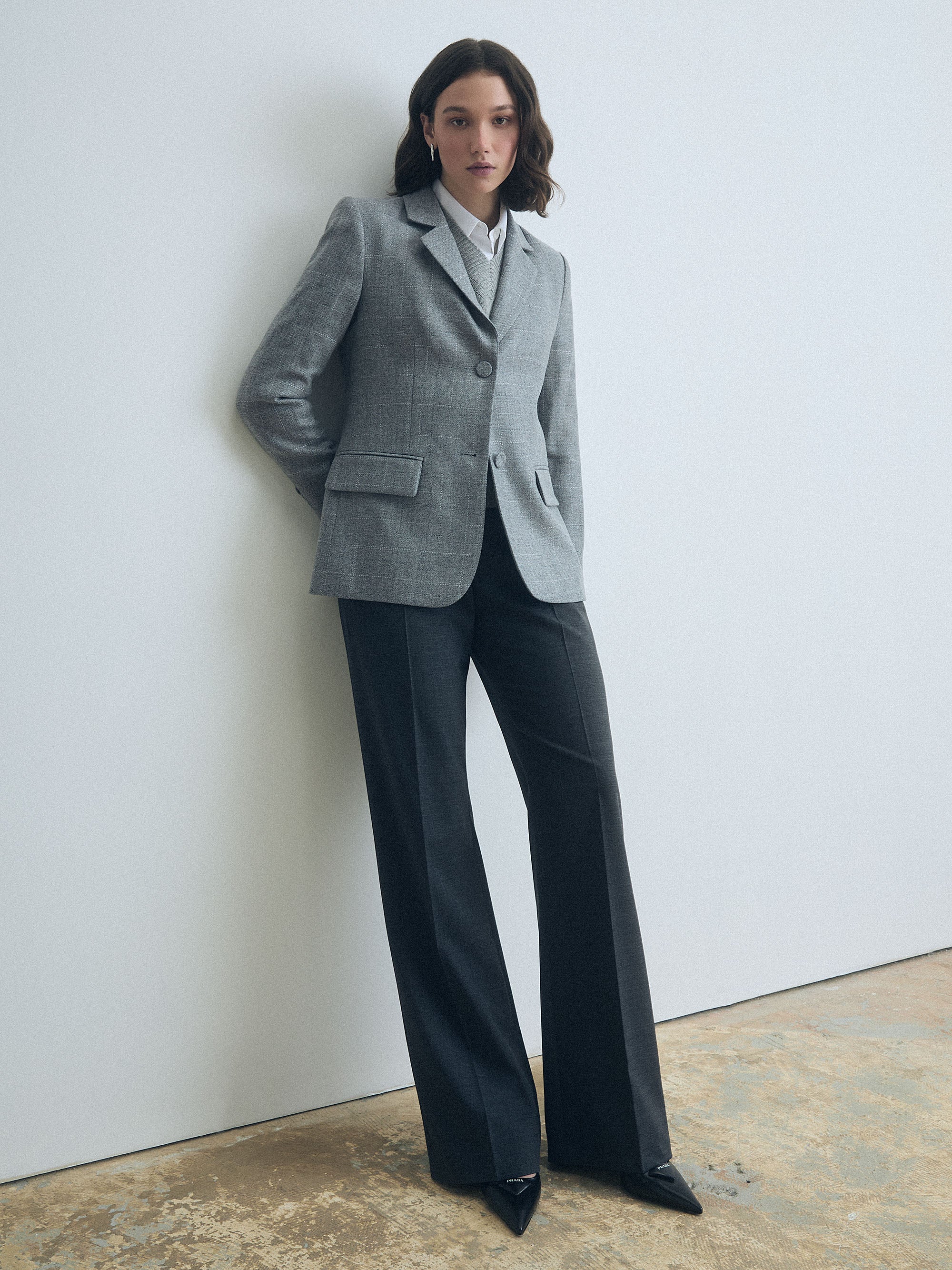 Woman wearing a gray blazer and Grey wool-blend pants with adjustable waist tabs by Judith & Charles  against a white wall.