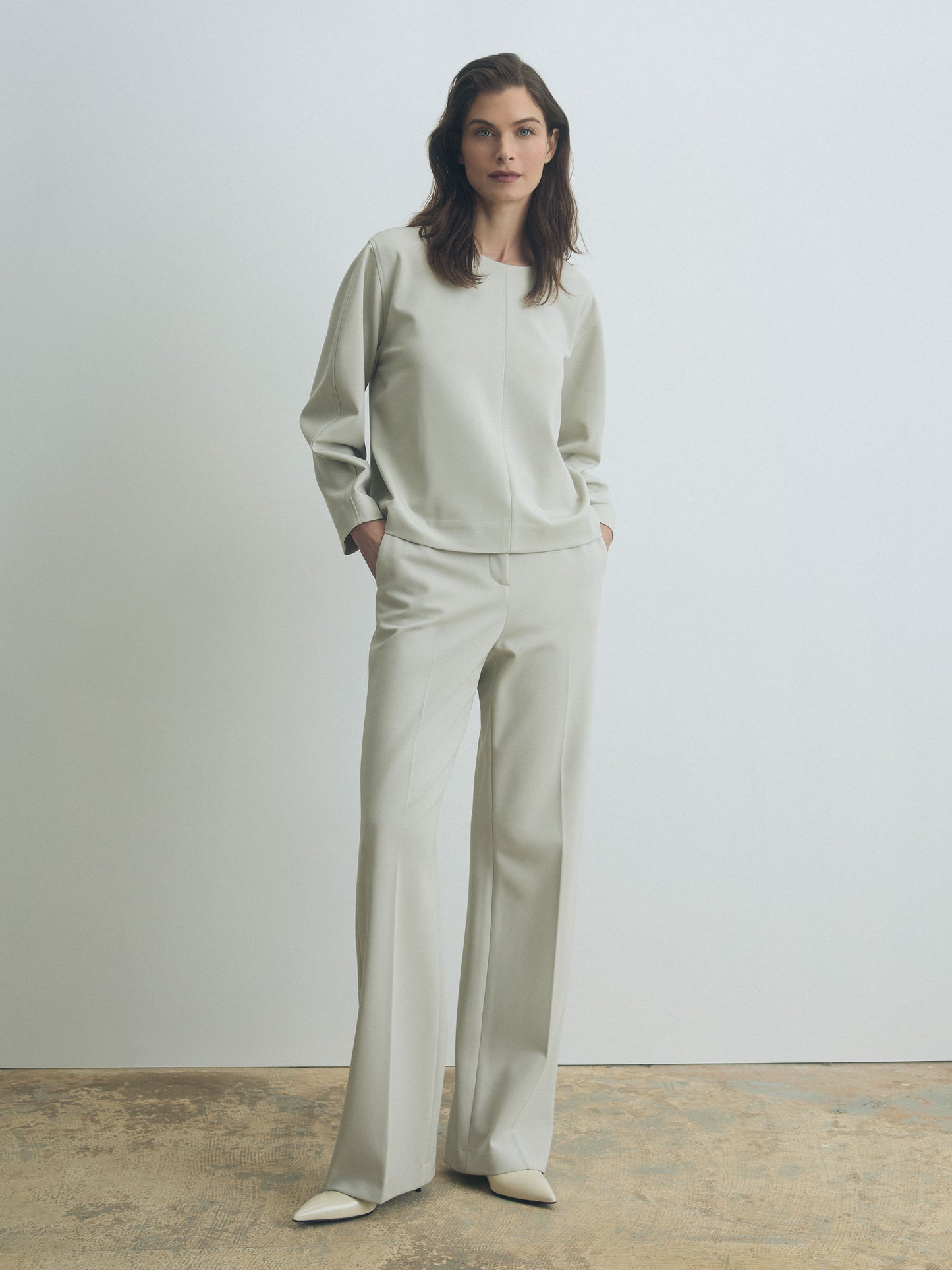 Woman wearing a light gray outfit against a plain background