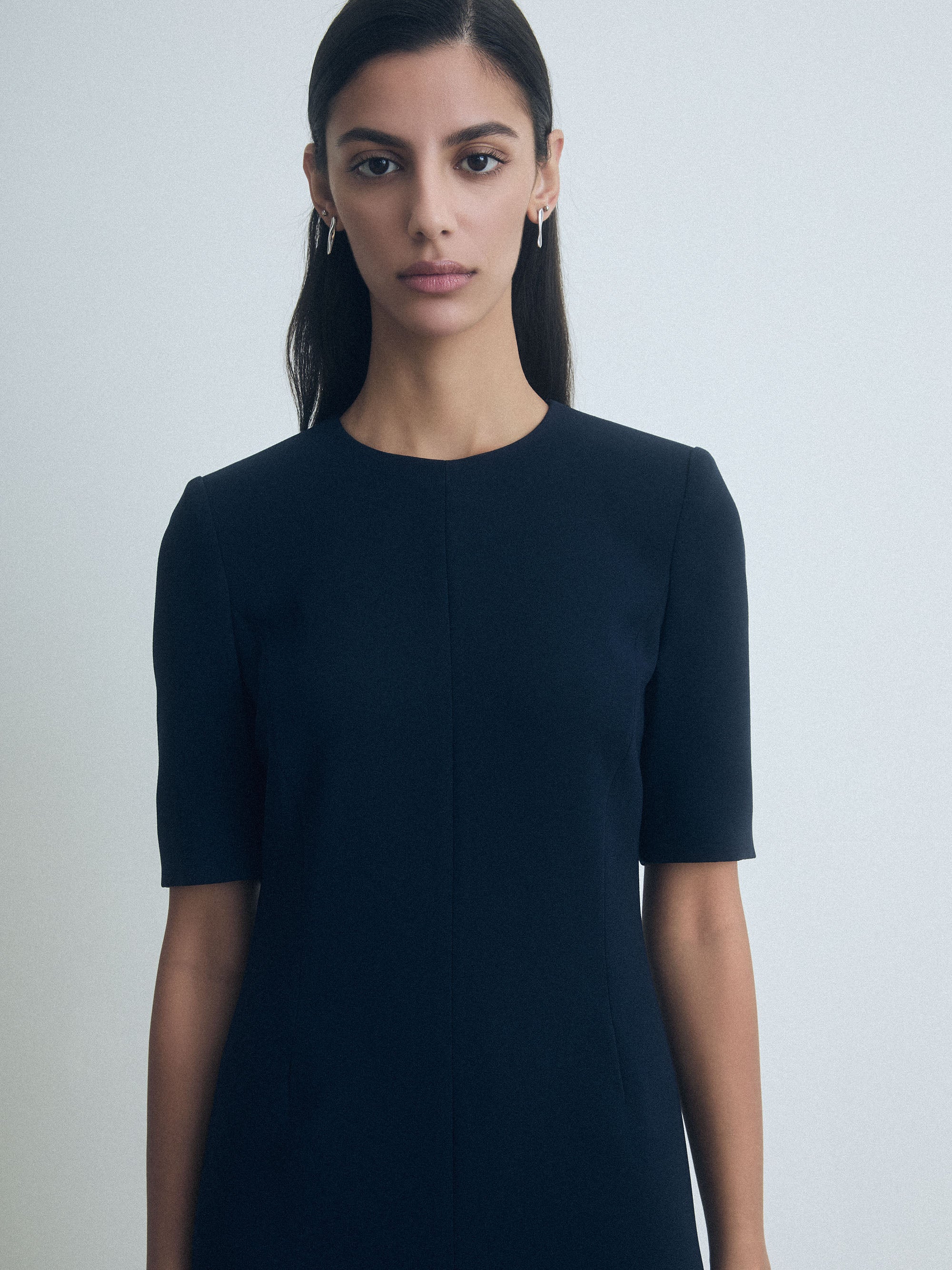 Woman wearing a navy blue dress against a light gray background