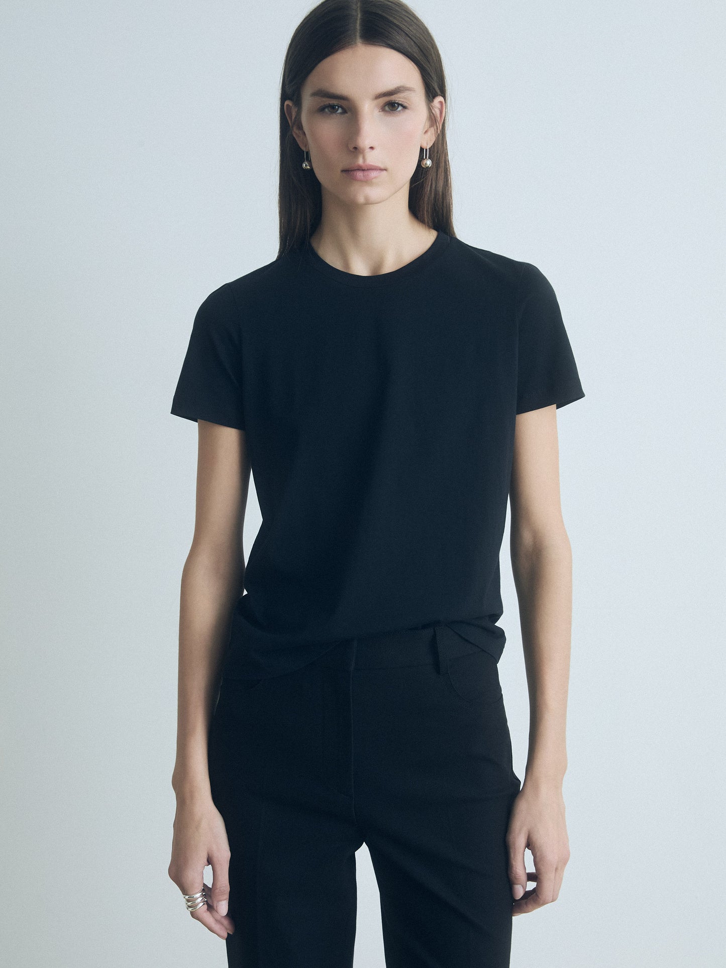 Person wearing a black t-shirt and pants on a light gray background