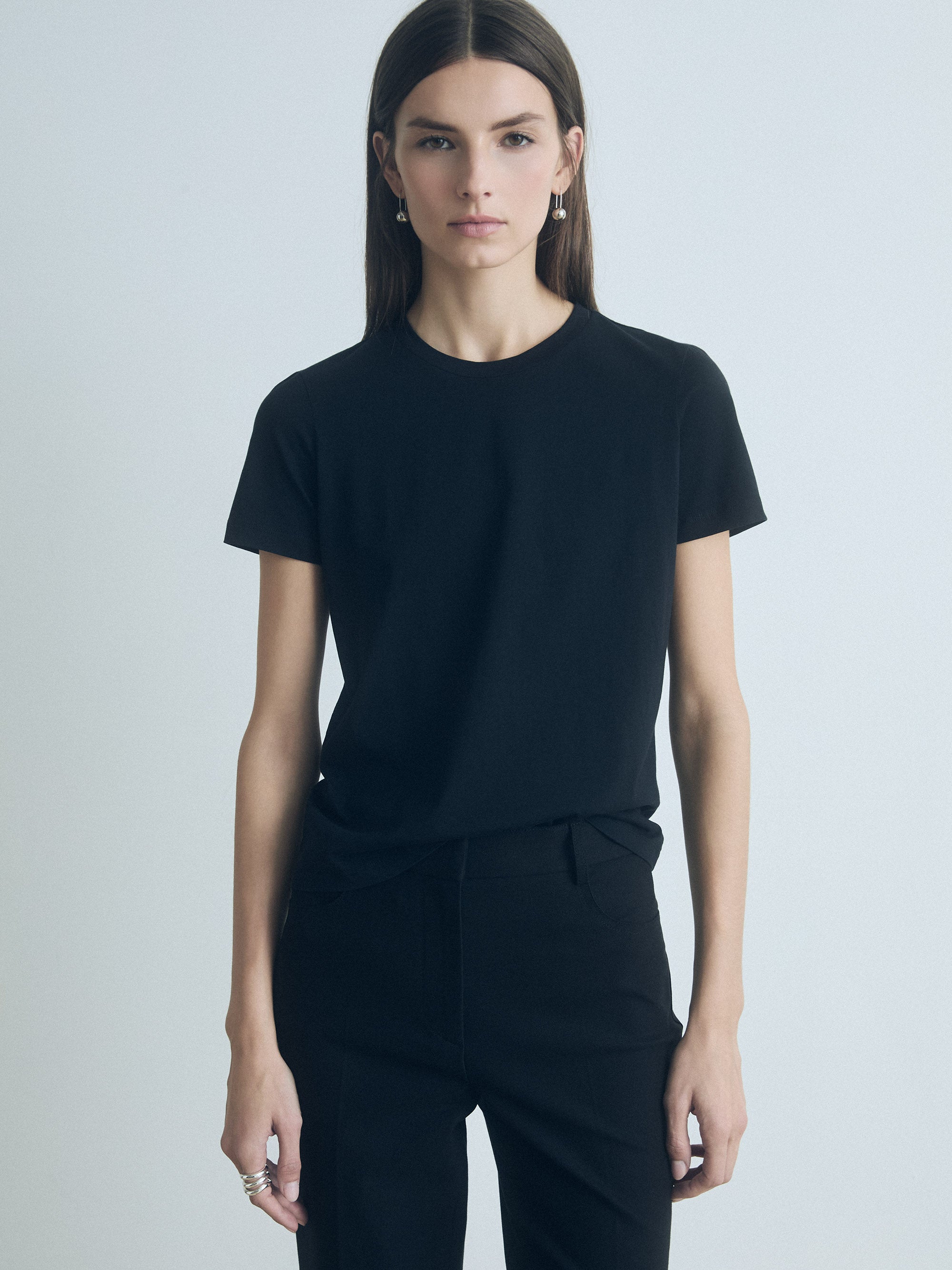 Person wearing a black t-shirt and pants on a light gray background