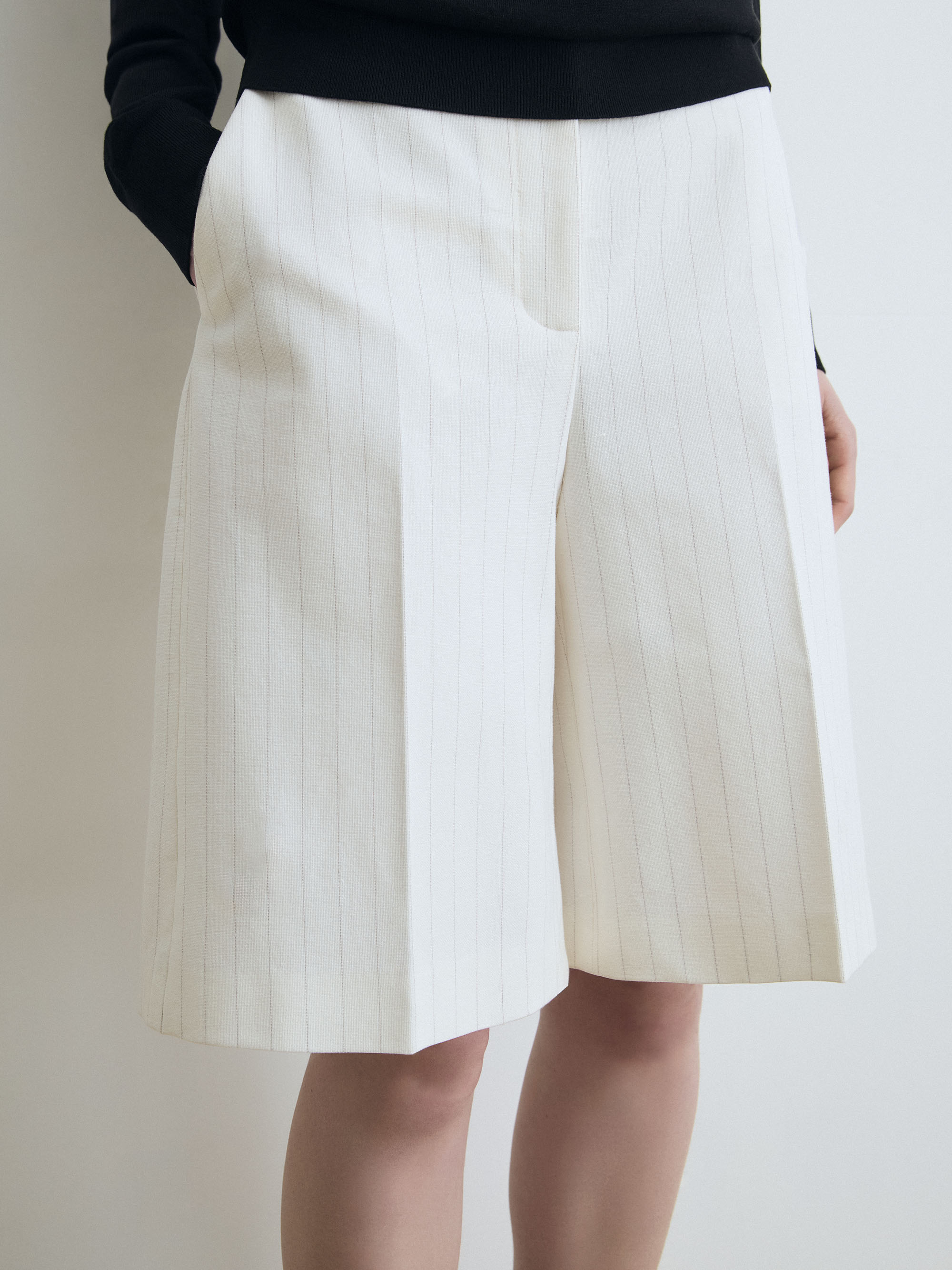White pleated  short worn by a person on a plain background