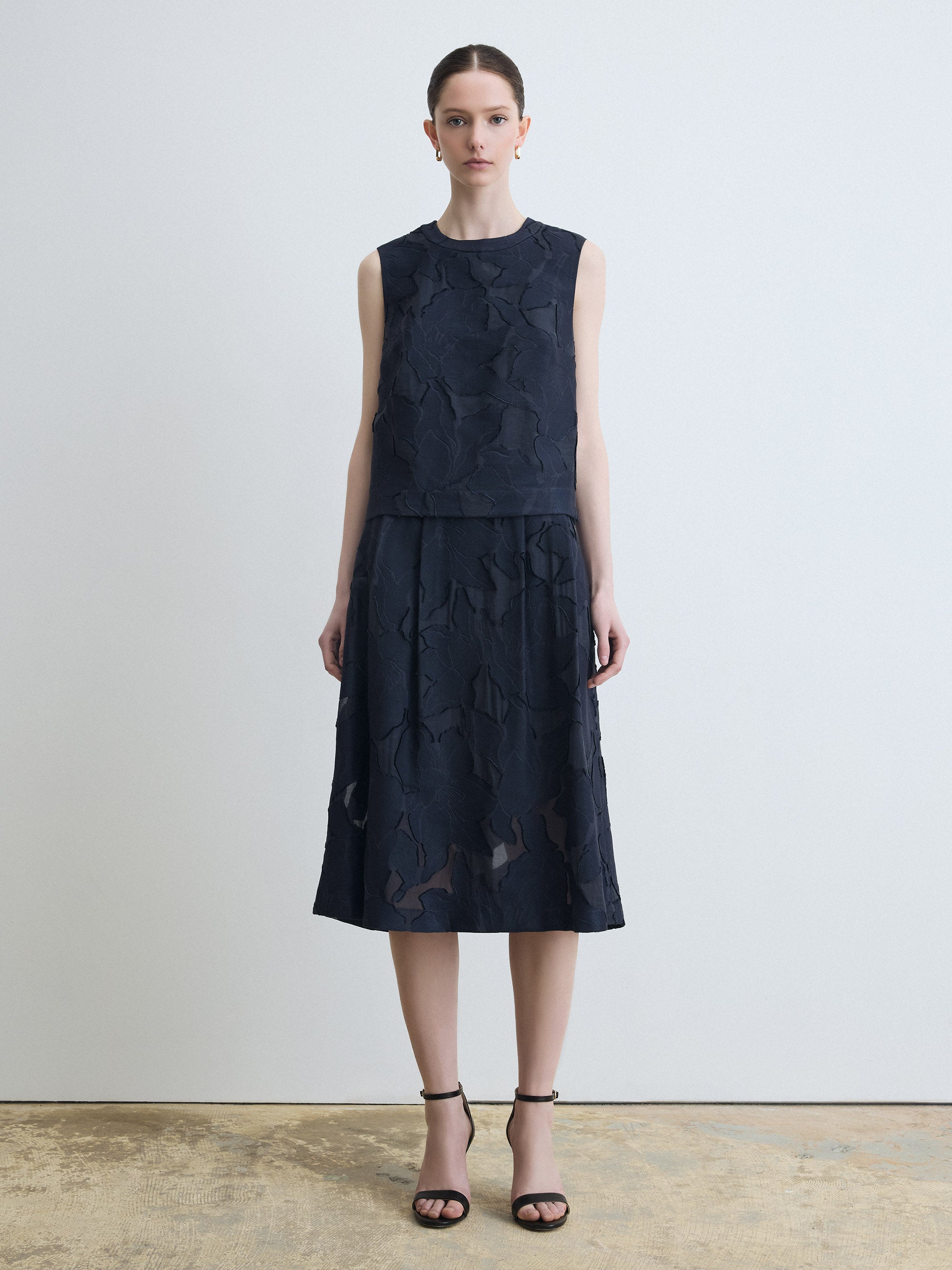 Woman wearing a sleeveless navy set against a plain background