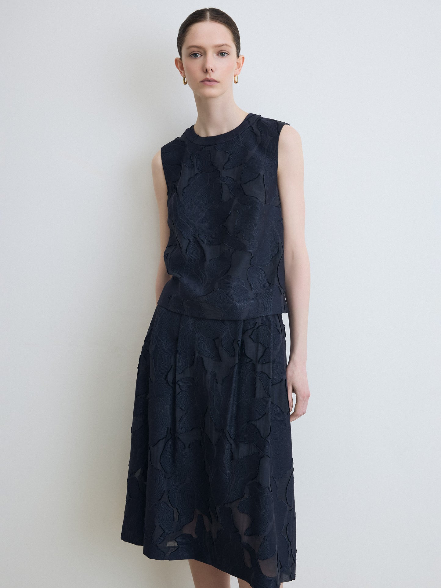 Woman wearing a dark blue sleeveless set against a white background