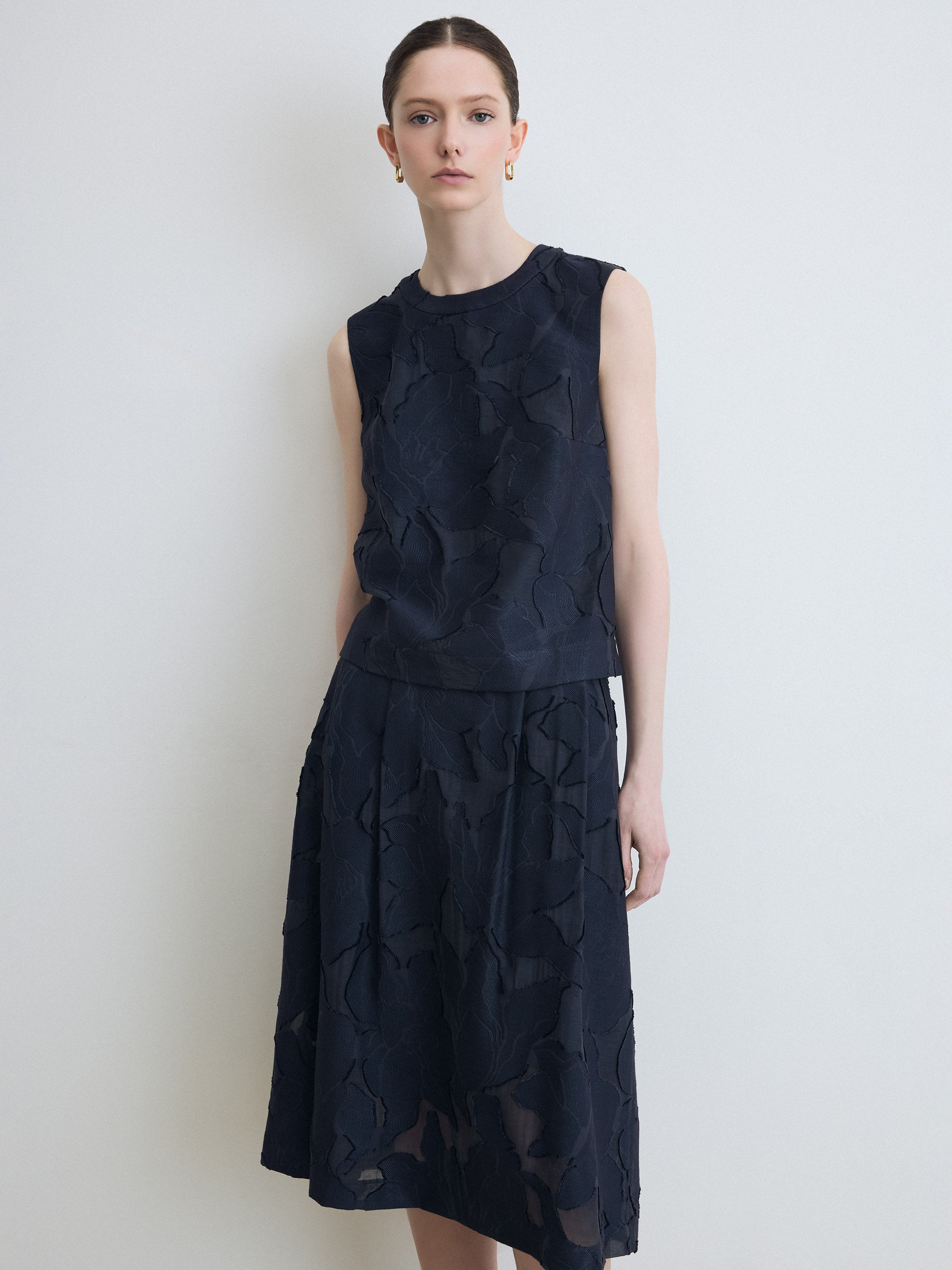 Woman wearing a dark blue sleeveless set against a white background