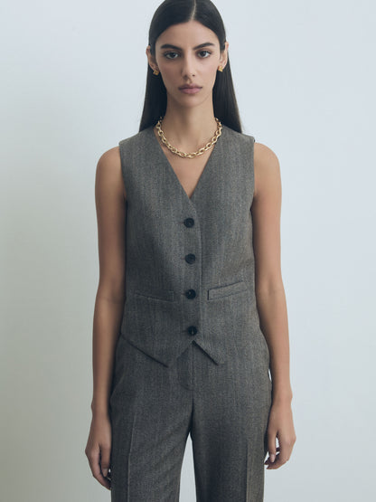 Woman wearing a taupe judith and charles suit vest and pants on a plain background