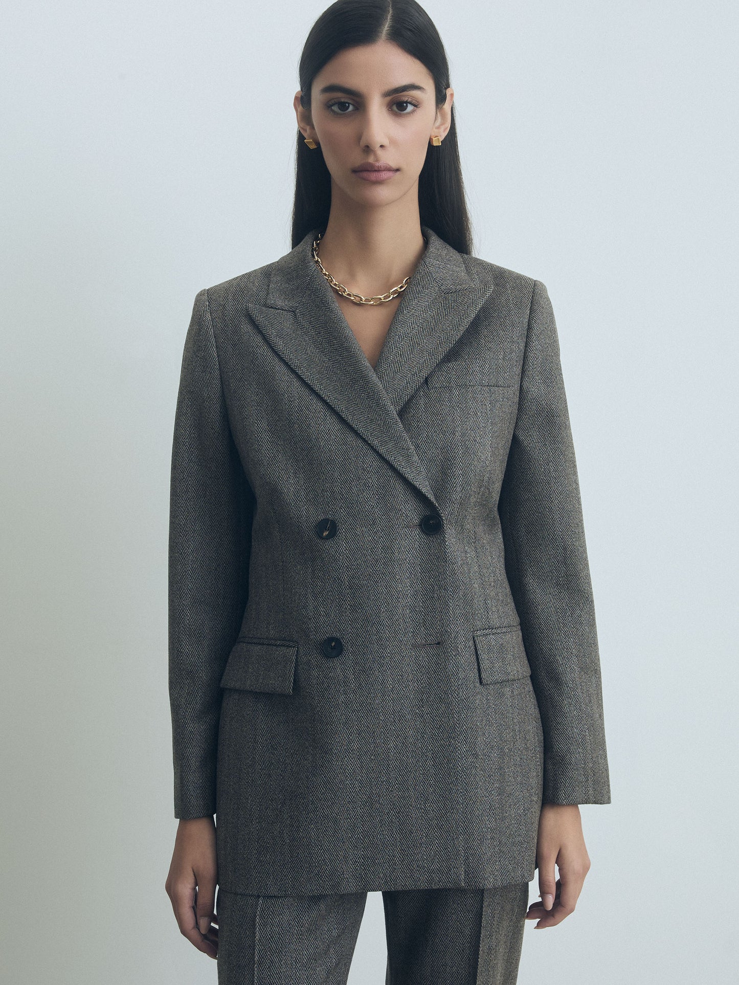 Woman wearing a taupe judith and charles blazer against a plain background