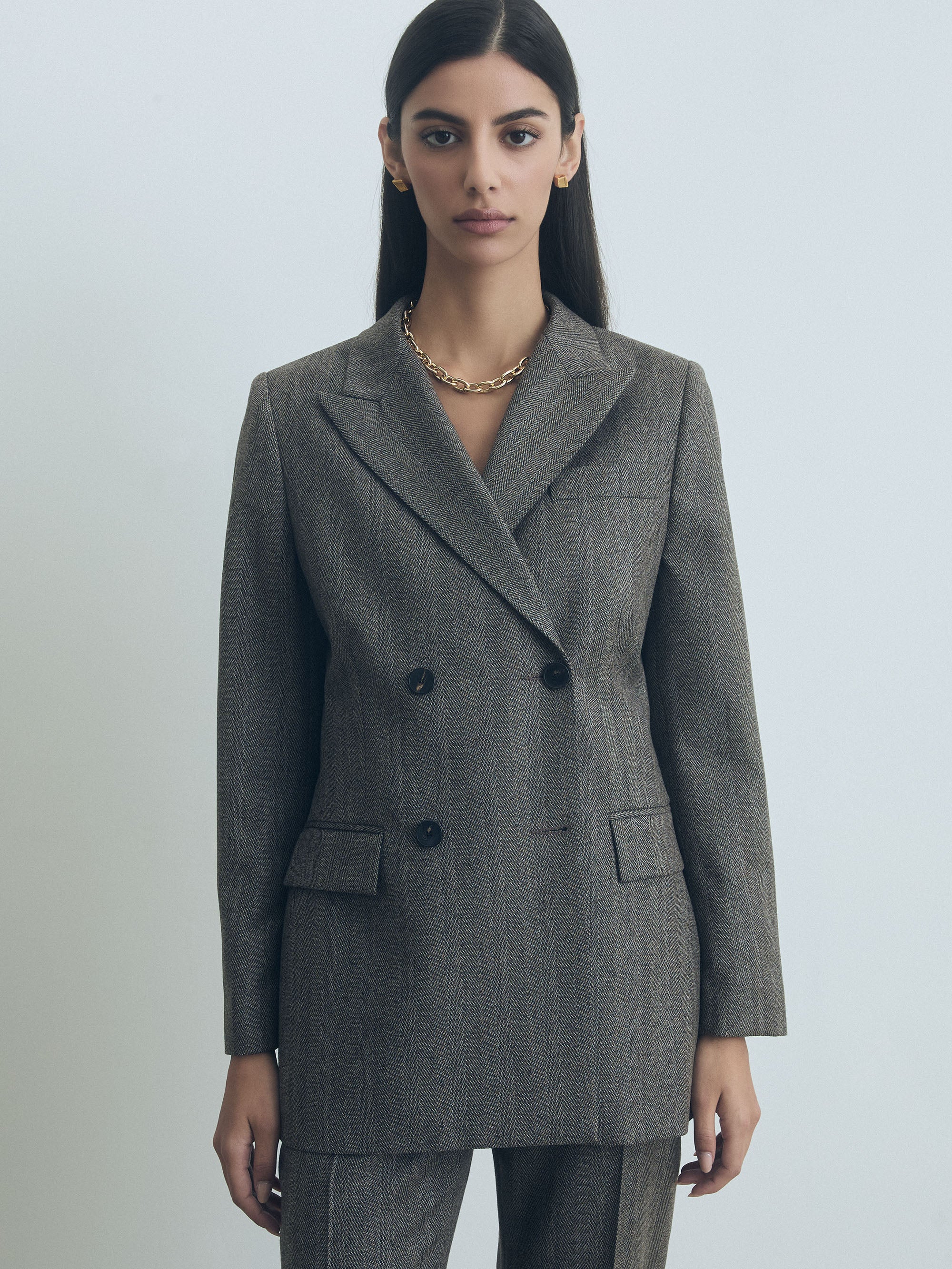 Woman wearing a taupe judith and charles blazer against a plain background