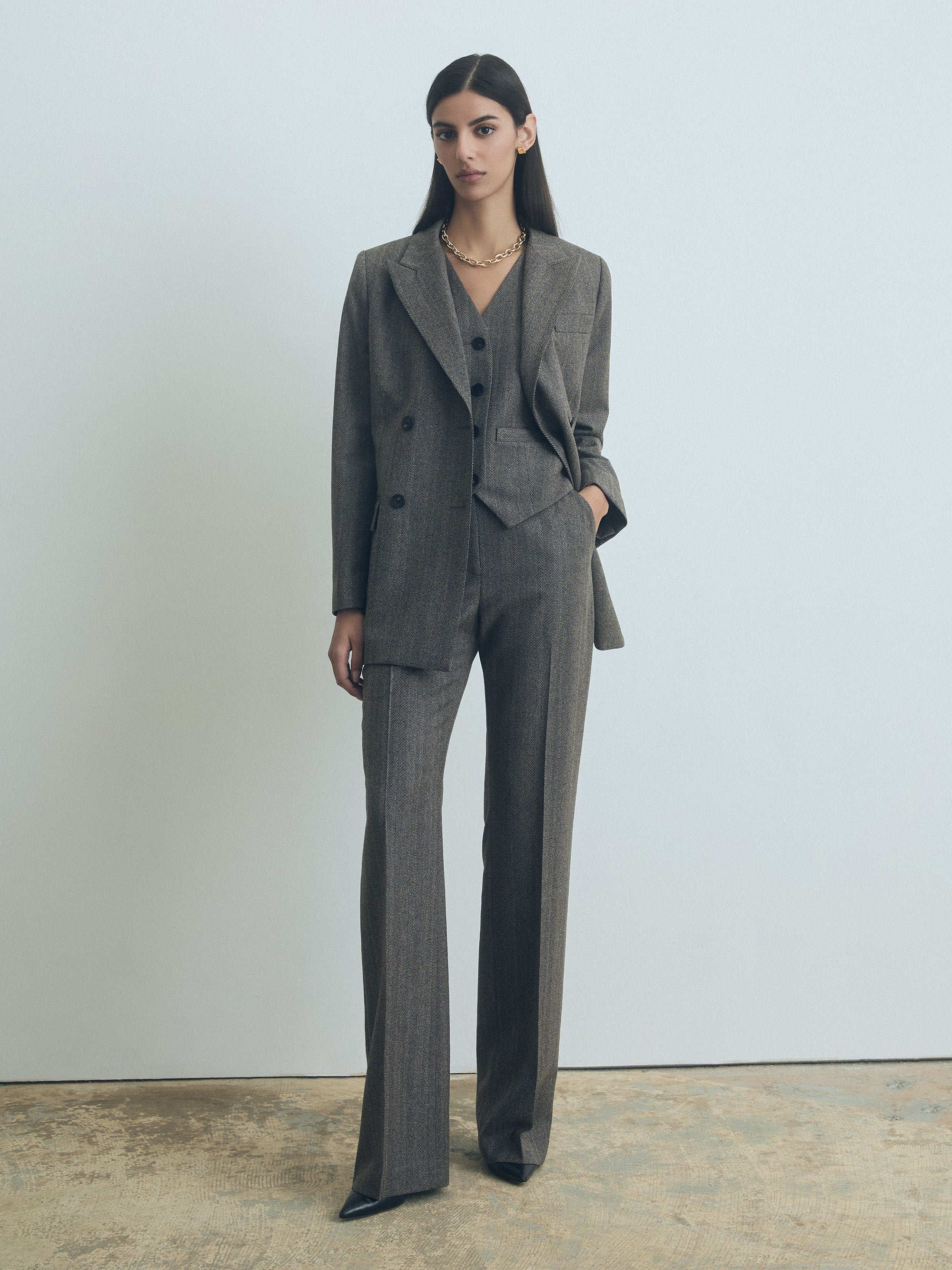 Model wearing Judith and Charles slight fit-to-flare herringbone wool pants with slash and back welt pockets, belt loops, unlined, made in Canada, taupe