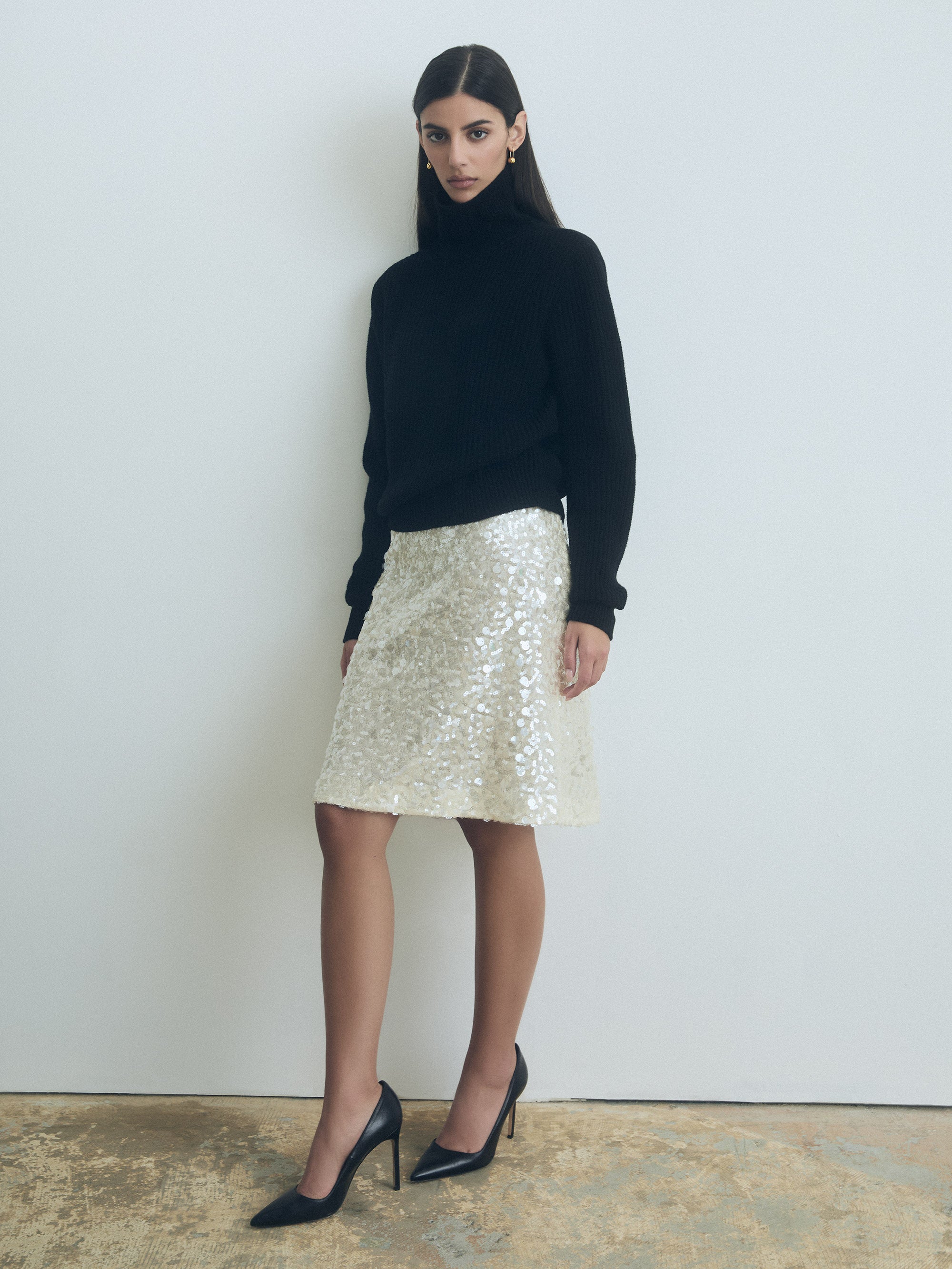 Woman wearing a black turtleneck and Oyster straight sequin skirt with clean waist and back slit from Judith and Charles
