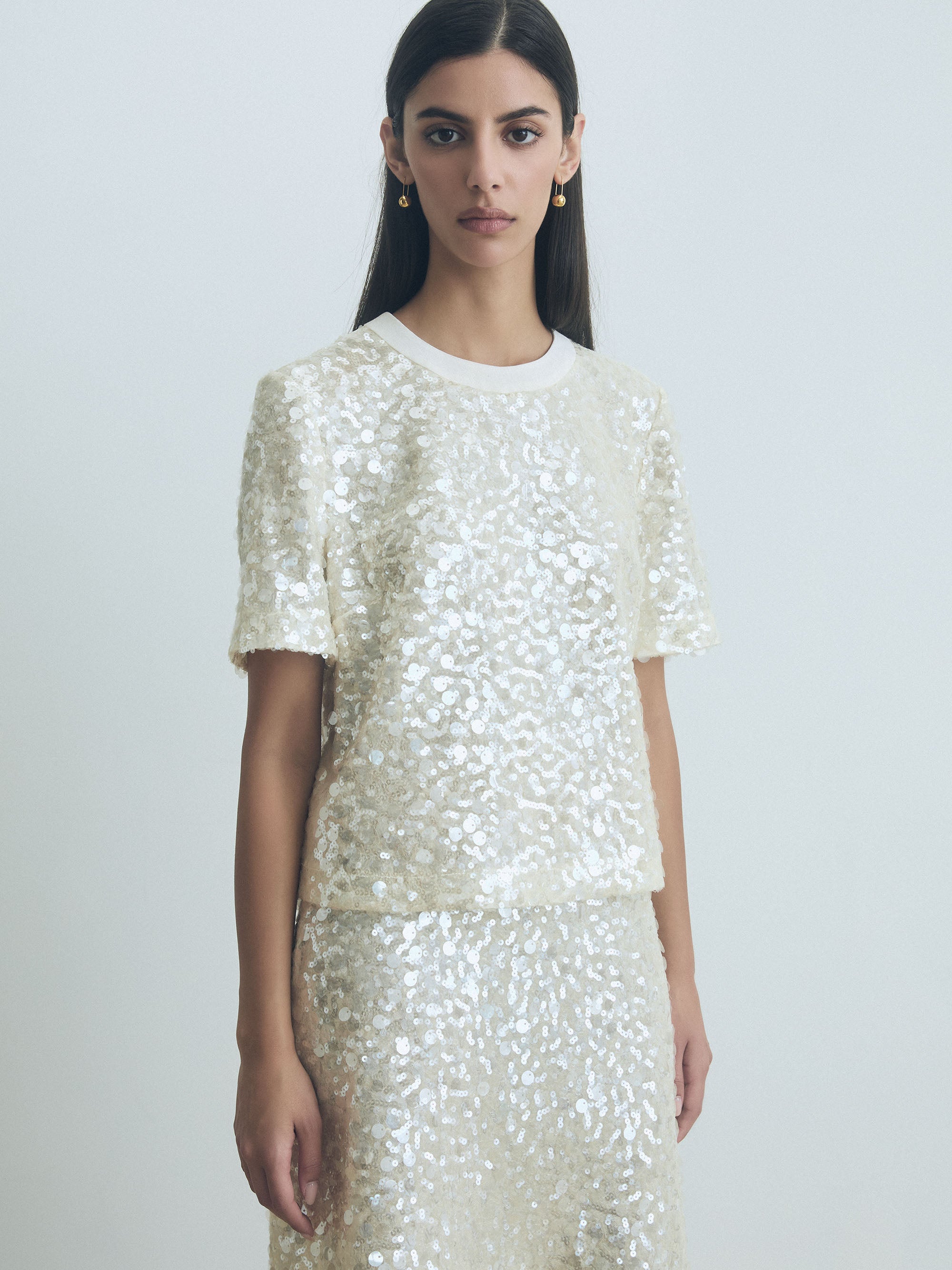 Model wearing an Oyster white sequin top and skirt against a plain background