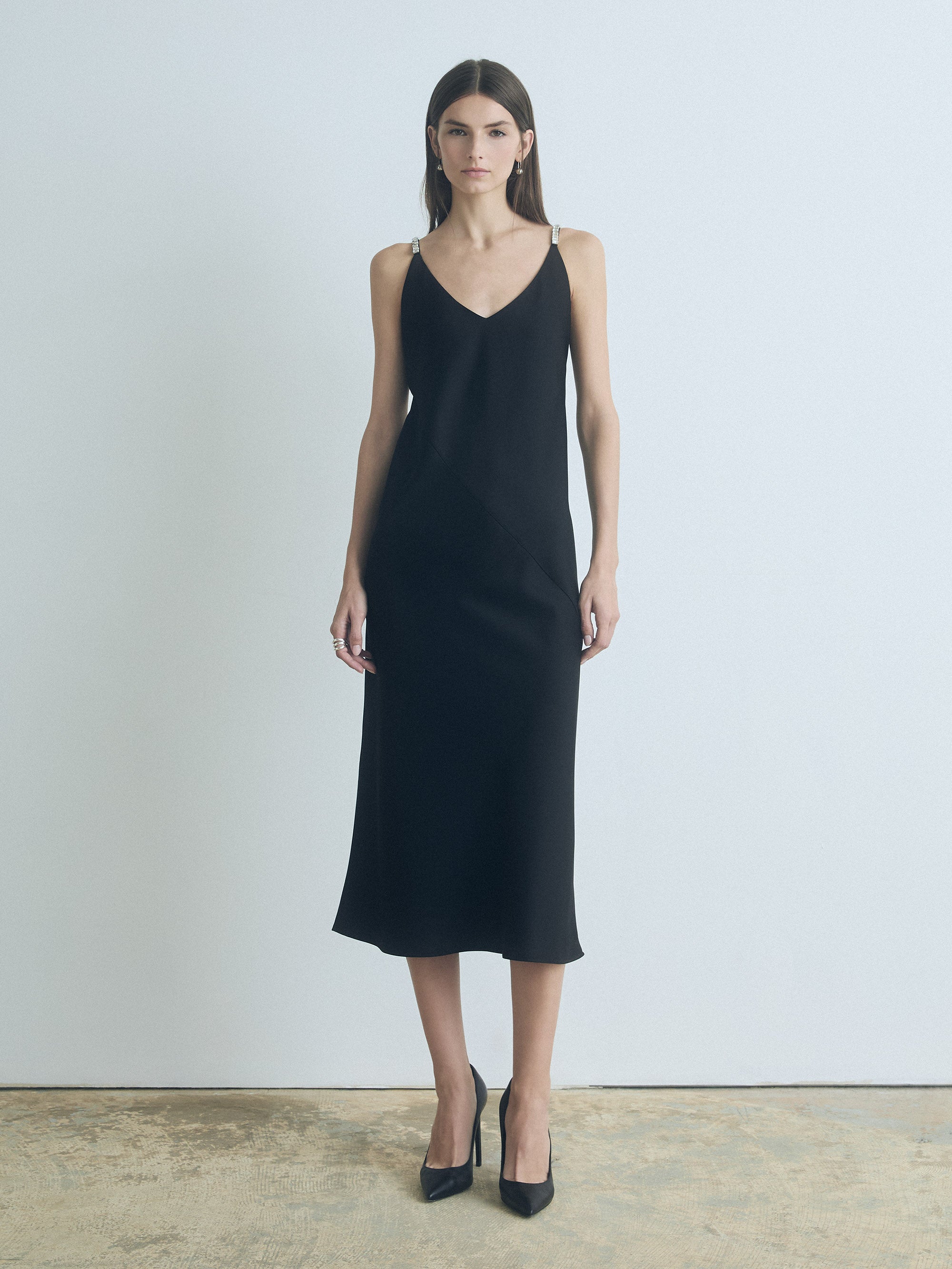 Model wearing black judith and charles Pearle satin bias slip dress with V-neck and shoulder embellishments
