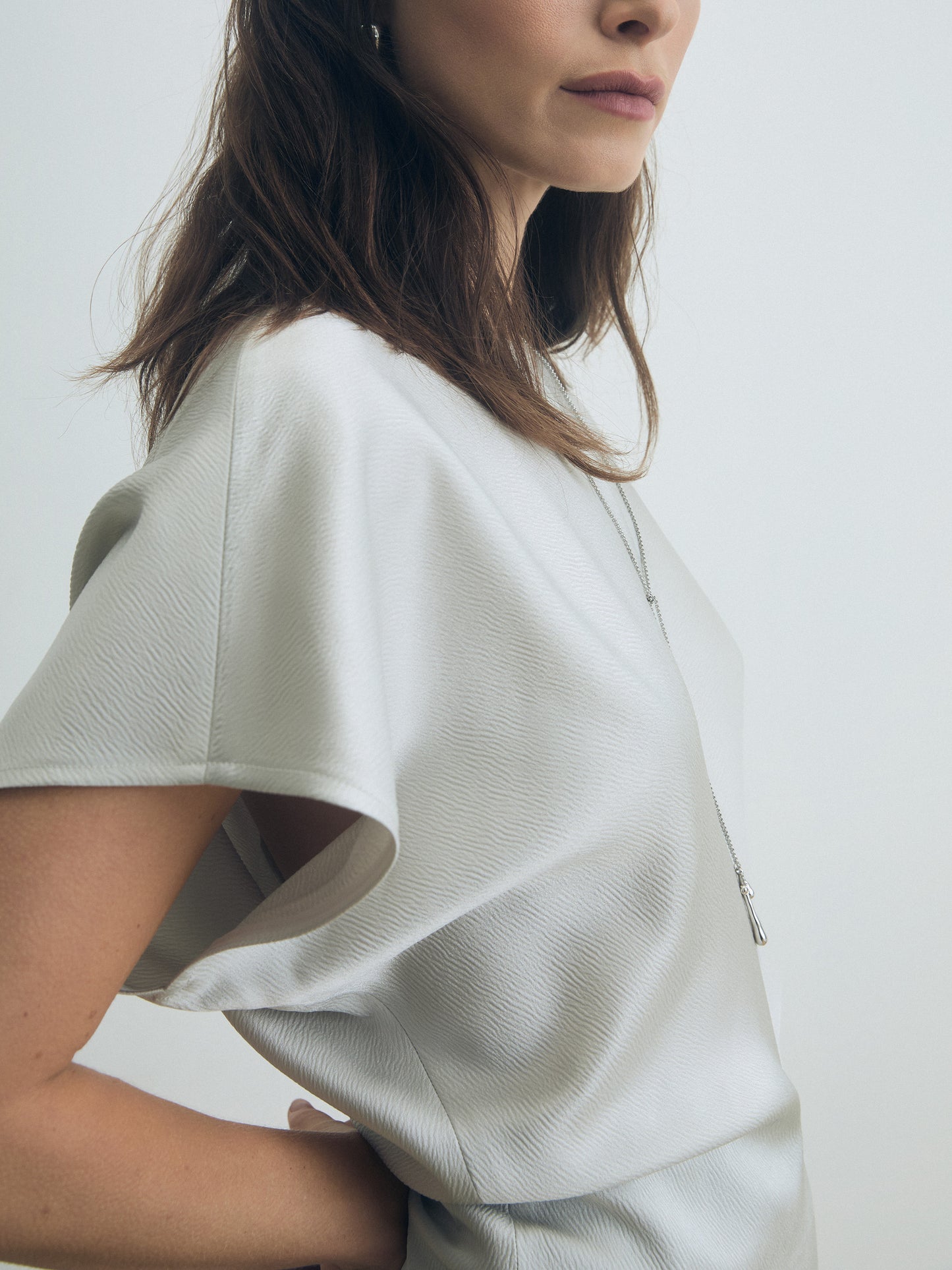 Person wearing a pearl textured shirt against a white background