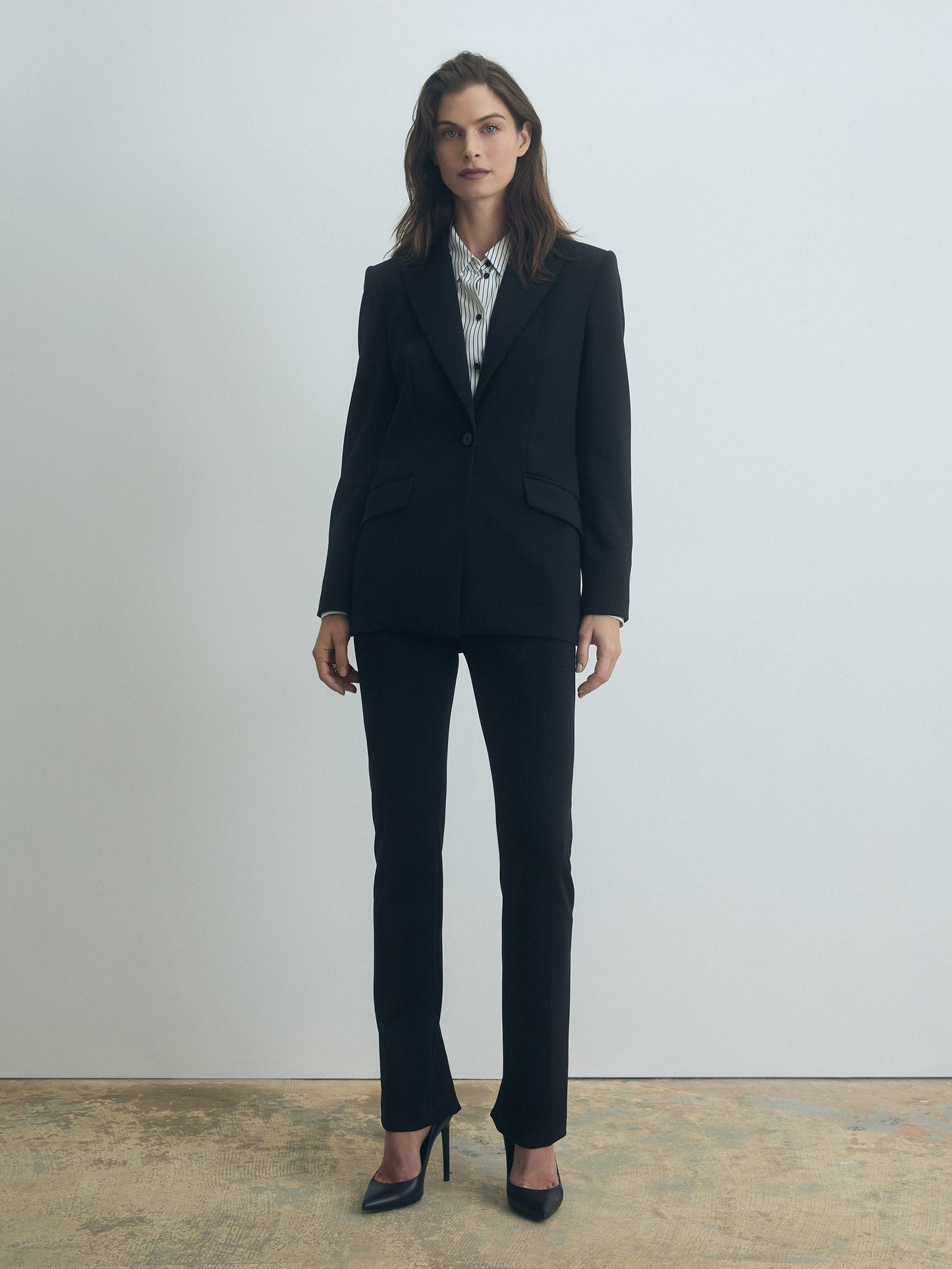 Woman wearing a black suit standing against a plain background