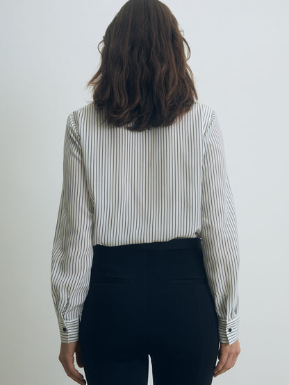 Person wearing a striped shirt and black pants against a white background