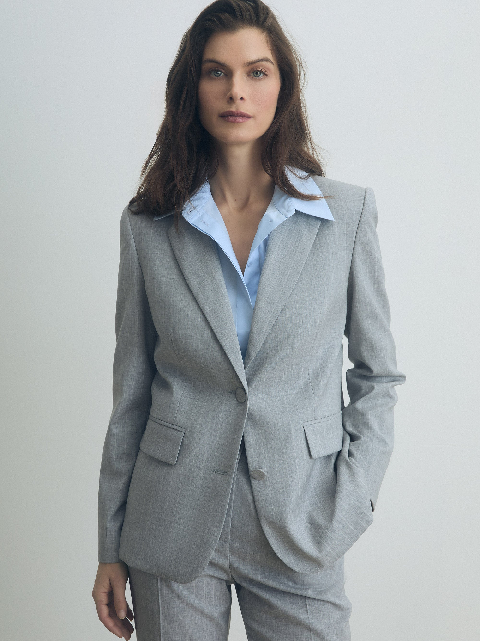 Grey pinstripe tailored jacket worn with matching trousers, styled with a light blue shirt.