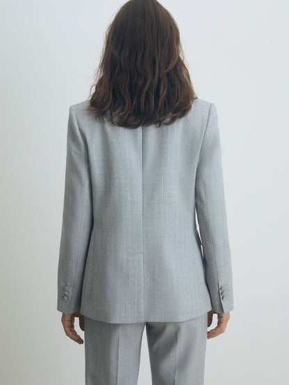 Person wearing a gray pinstripe suit against a white background