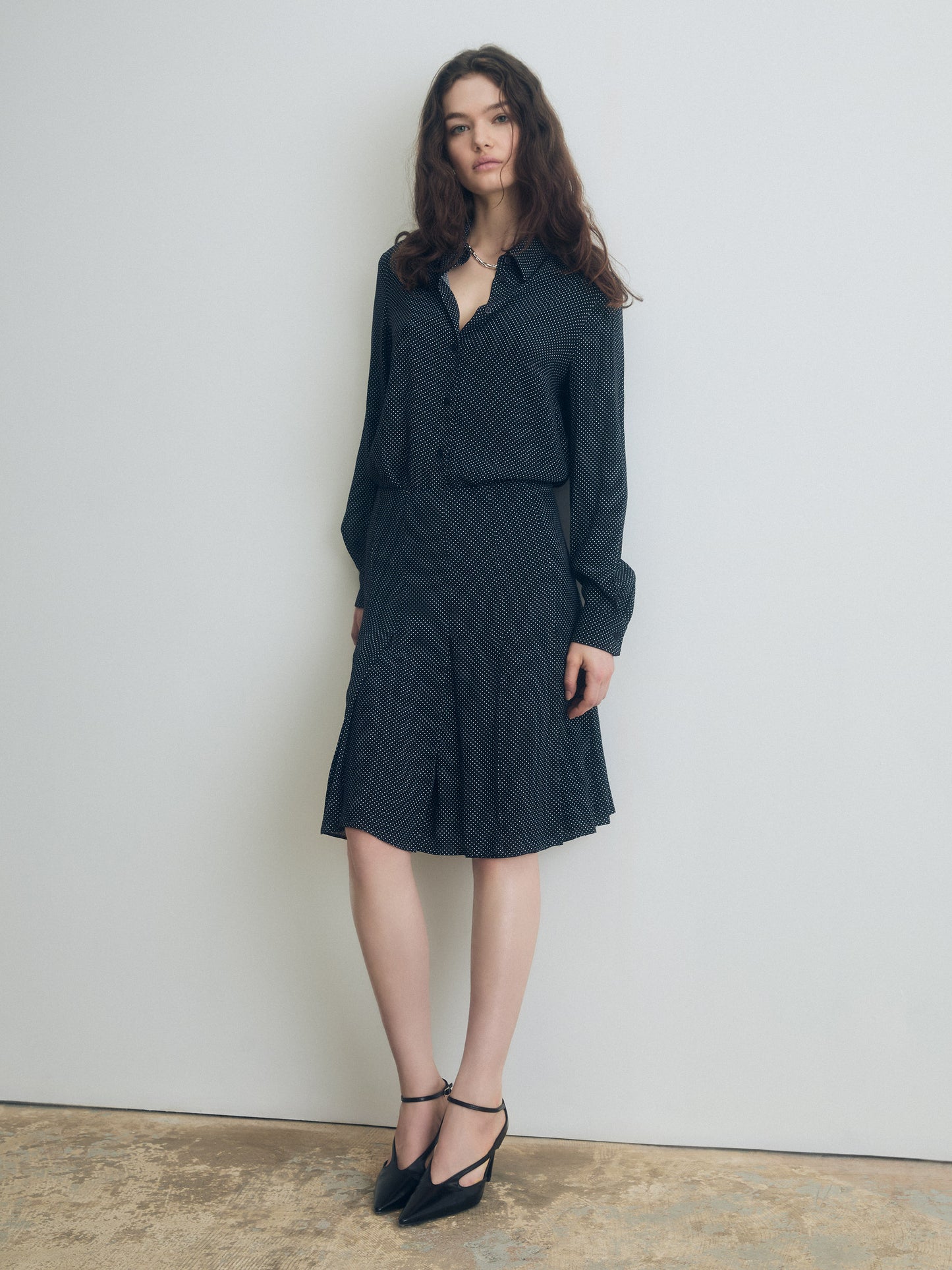 Woman wearing a black dotted outfit against a plain background