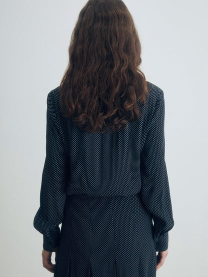 Person wearing a dark polka dot outfit against a white background