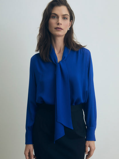 Woman wearing a bright blue blouse against a plain background