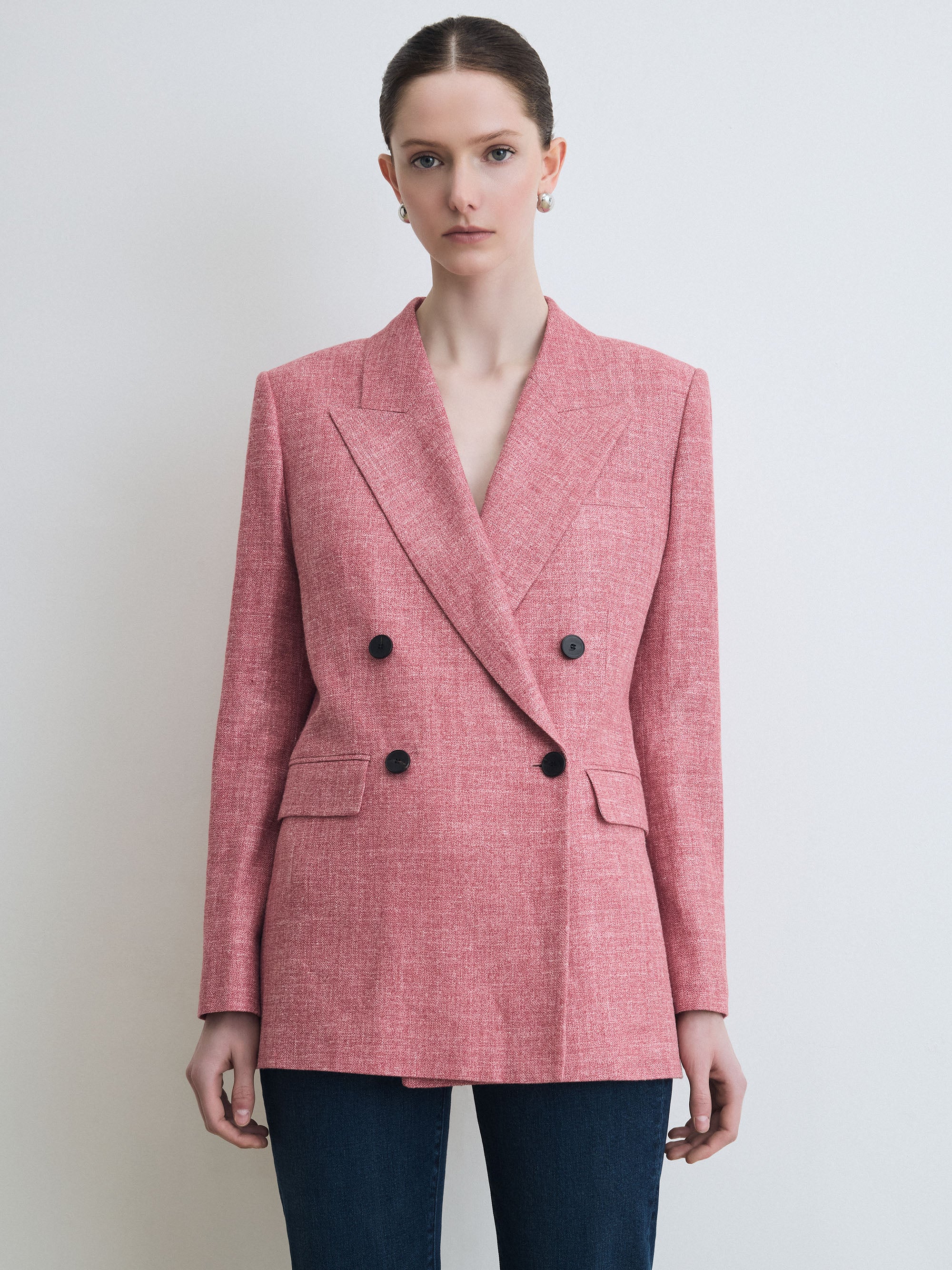 Woman wearing a red blazer with black buttons against a plain background