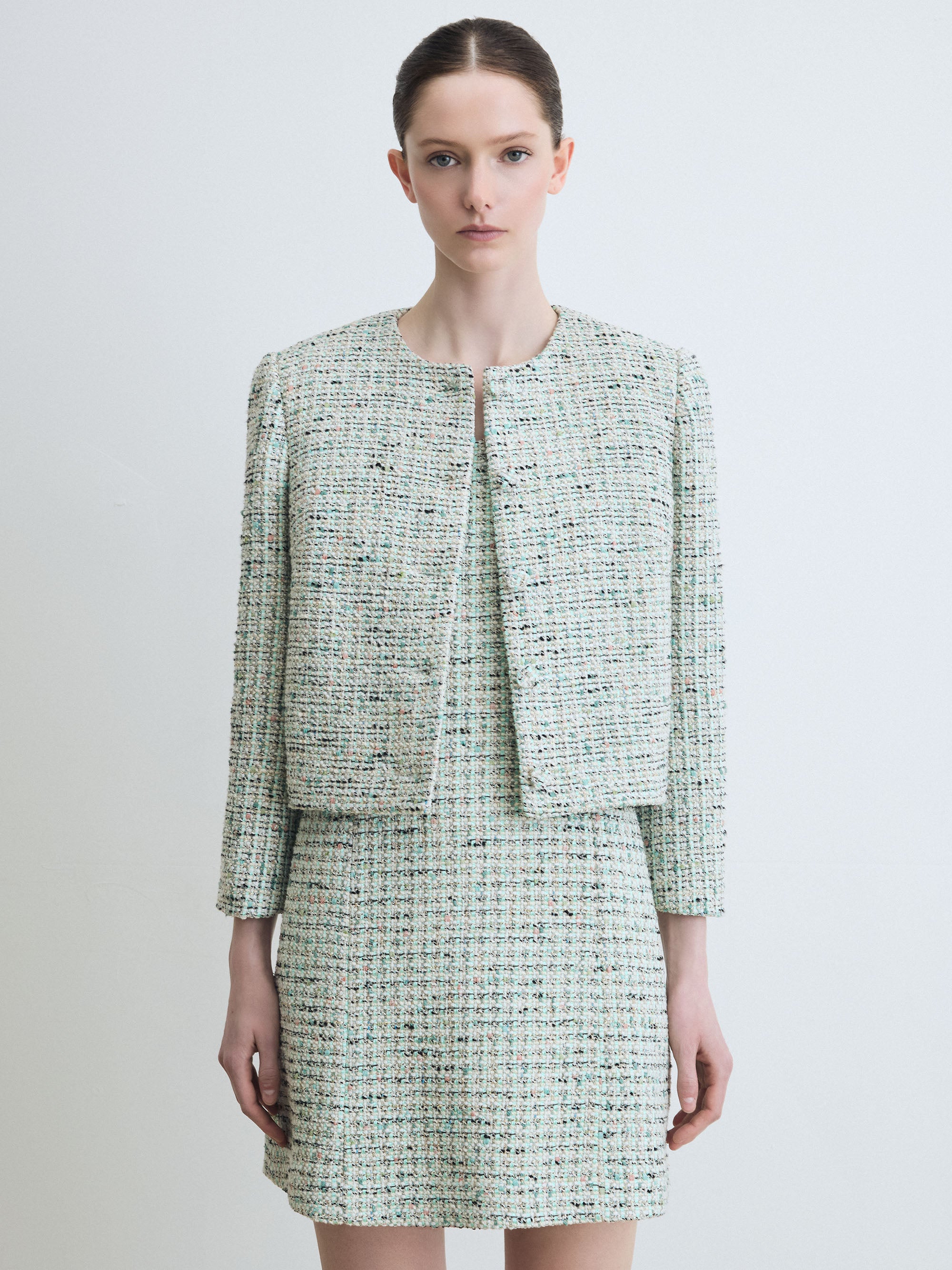 Woman wearing a mint tweed suit on a white background