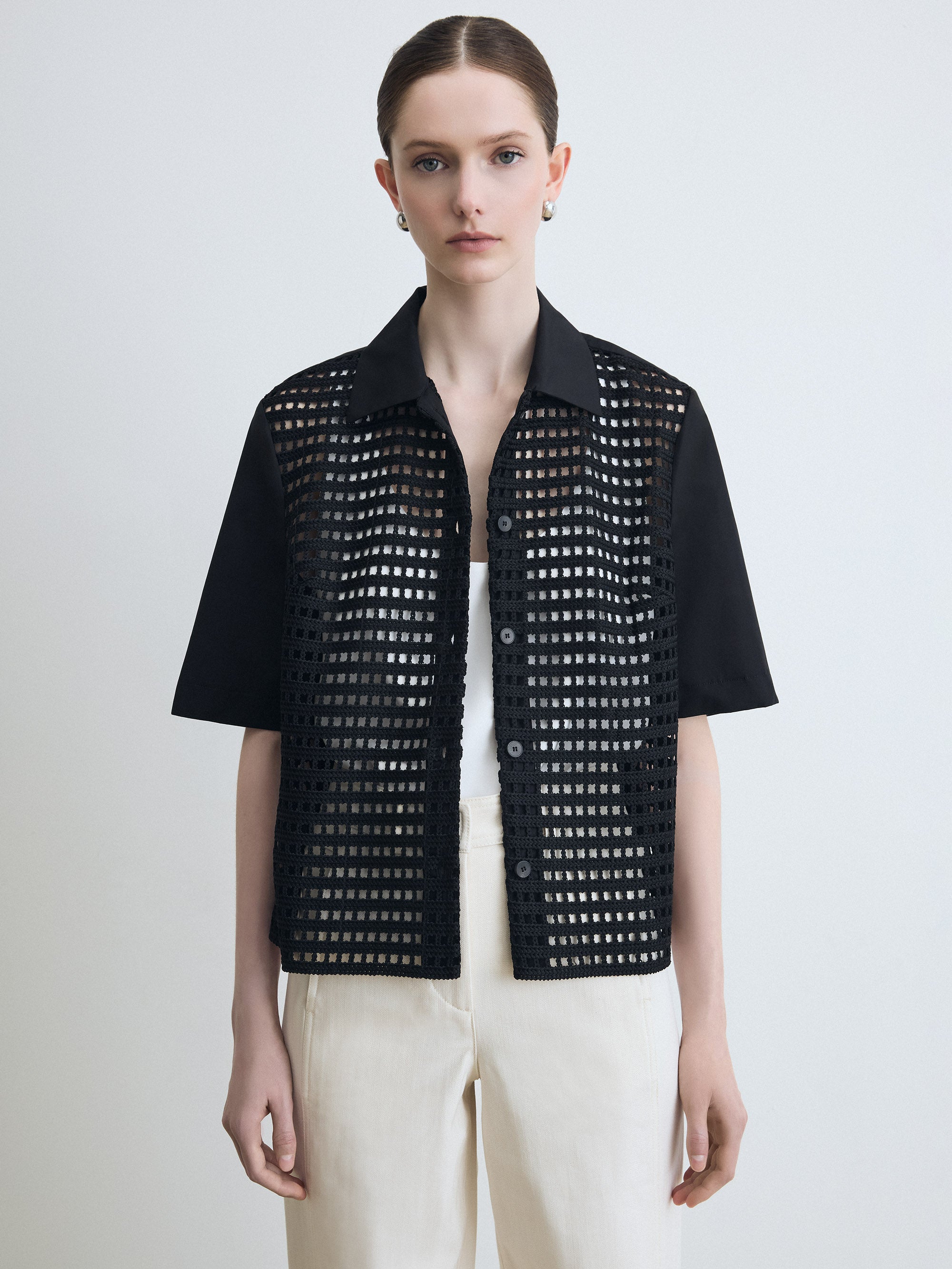 Person wearing a black perforated jacket on a white background