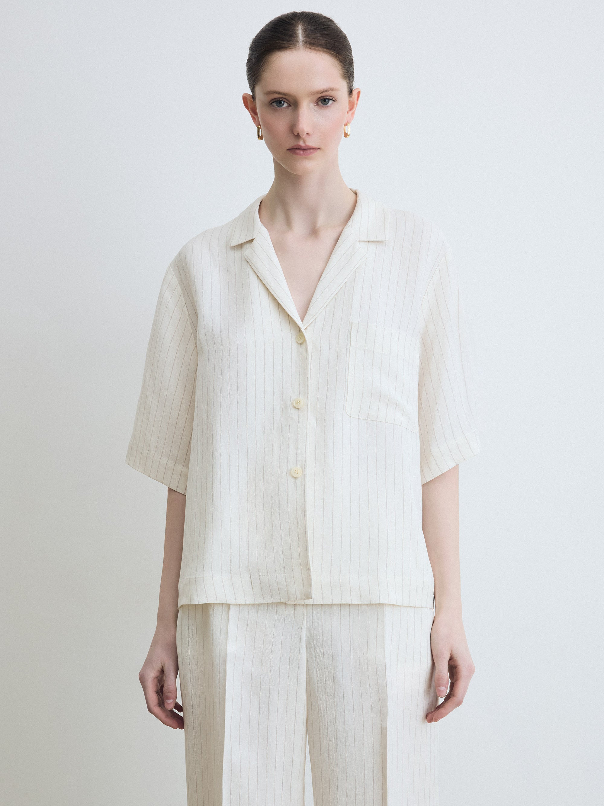 Woman wearing a light-colored outfit with a plain background