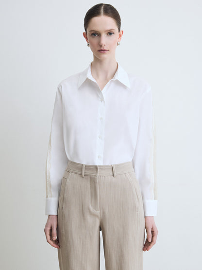 Person wearing a white shirt and beige pants on a plain background