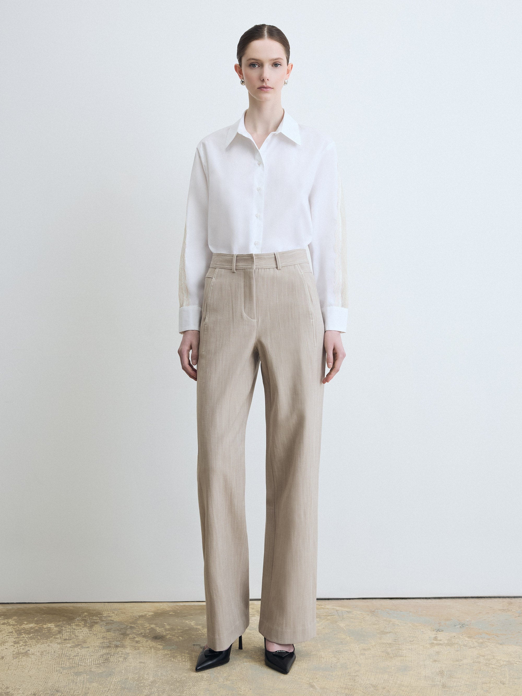 Person wearing a white shirt and beige pants against a plain background
