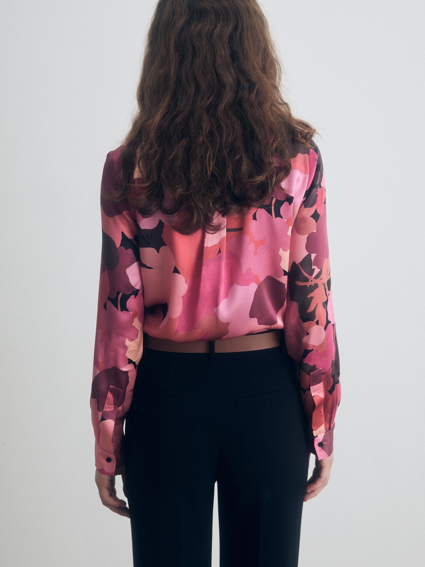 Person wearing a red floral blouse with long sleeves on a white background