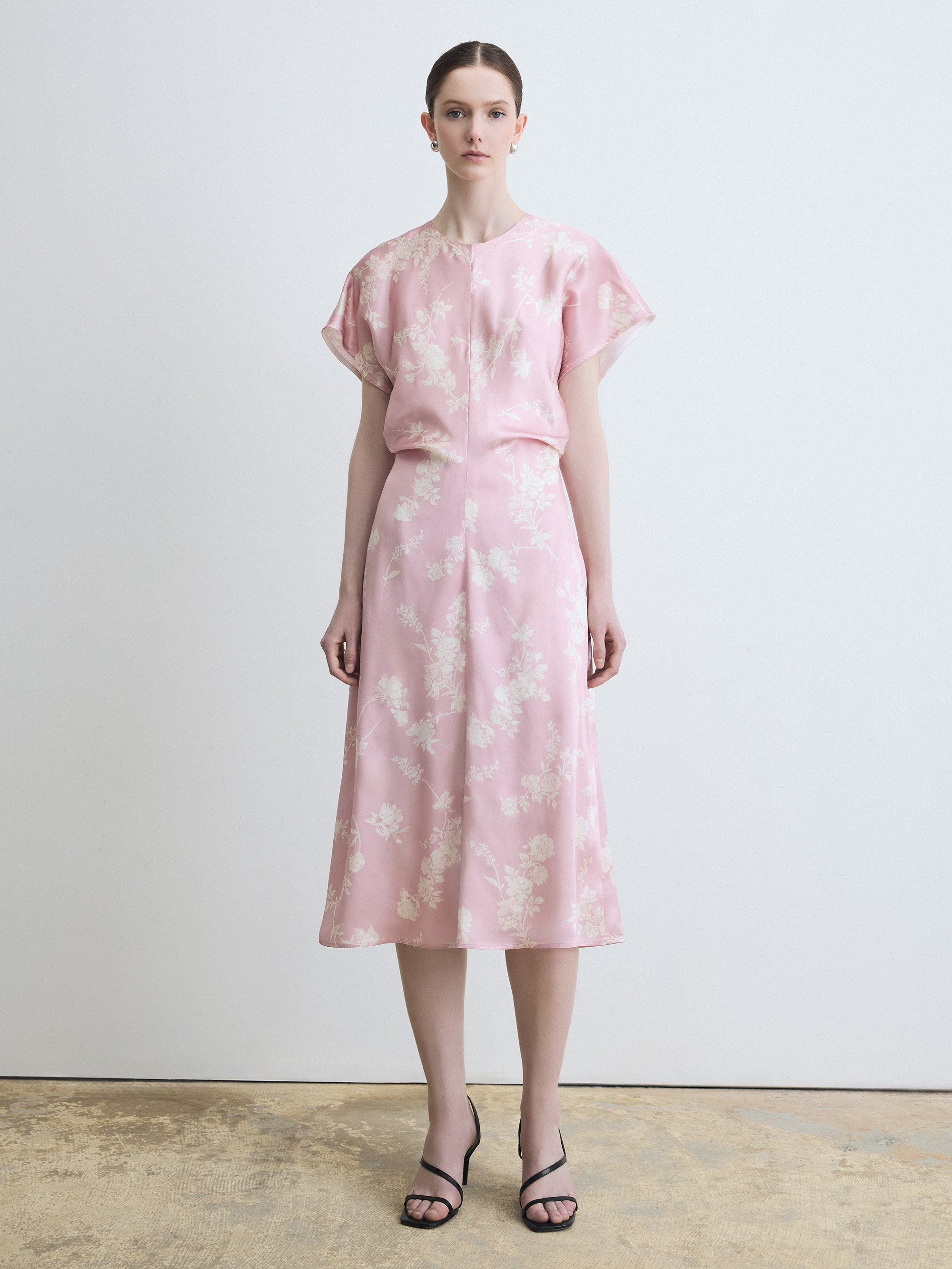 Woman wearing a pink floral dress against a plain background